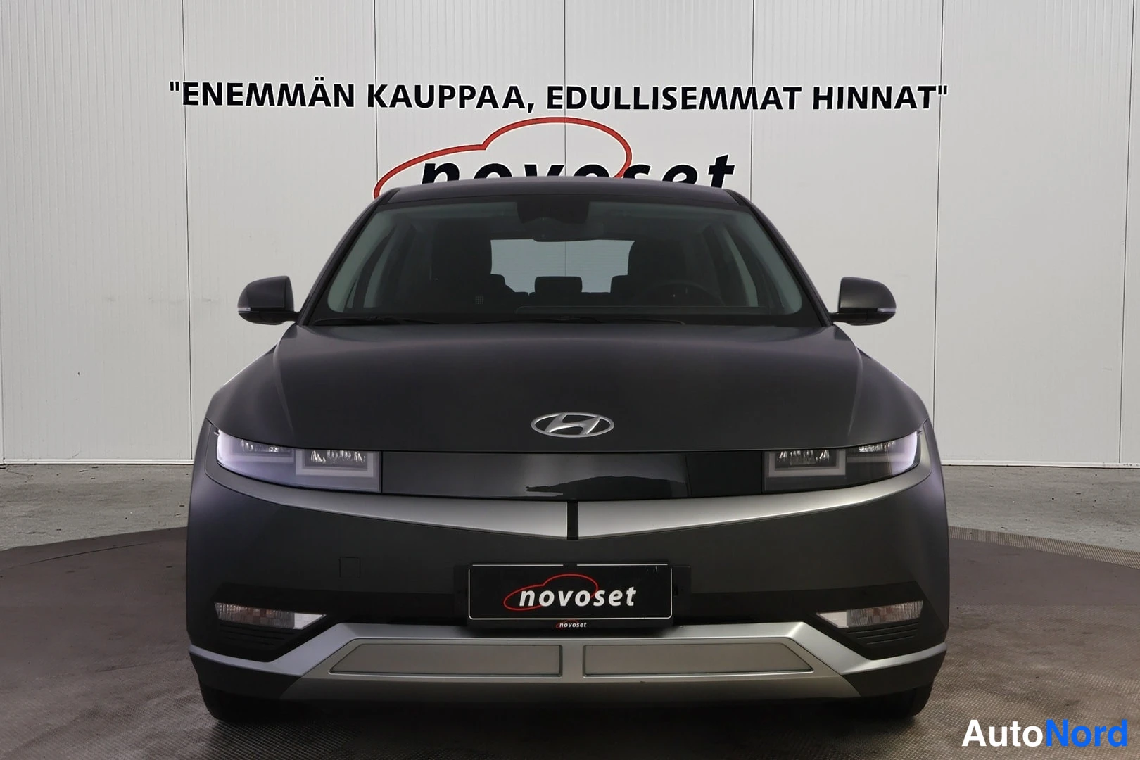 Edestä: Hyundai IONIQ 5:n etunäkymä suoraan edestä, keulalla nokka ja etupuskuri harmaassa studiossa.