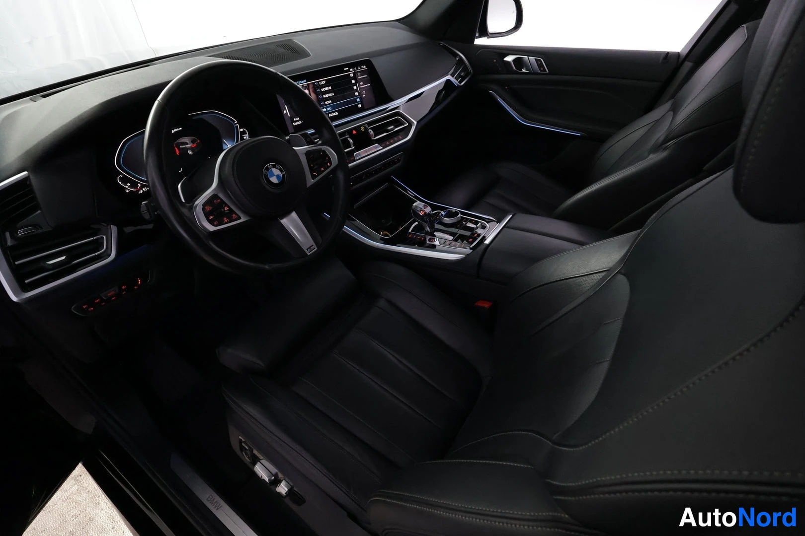 Edestä: Sisätilakuva etumatkalta: BMW-ohjauspyörä, digitaalinen mittaristo, kosketusnäyttö ja keskikonsolin iDrive-ohjain.