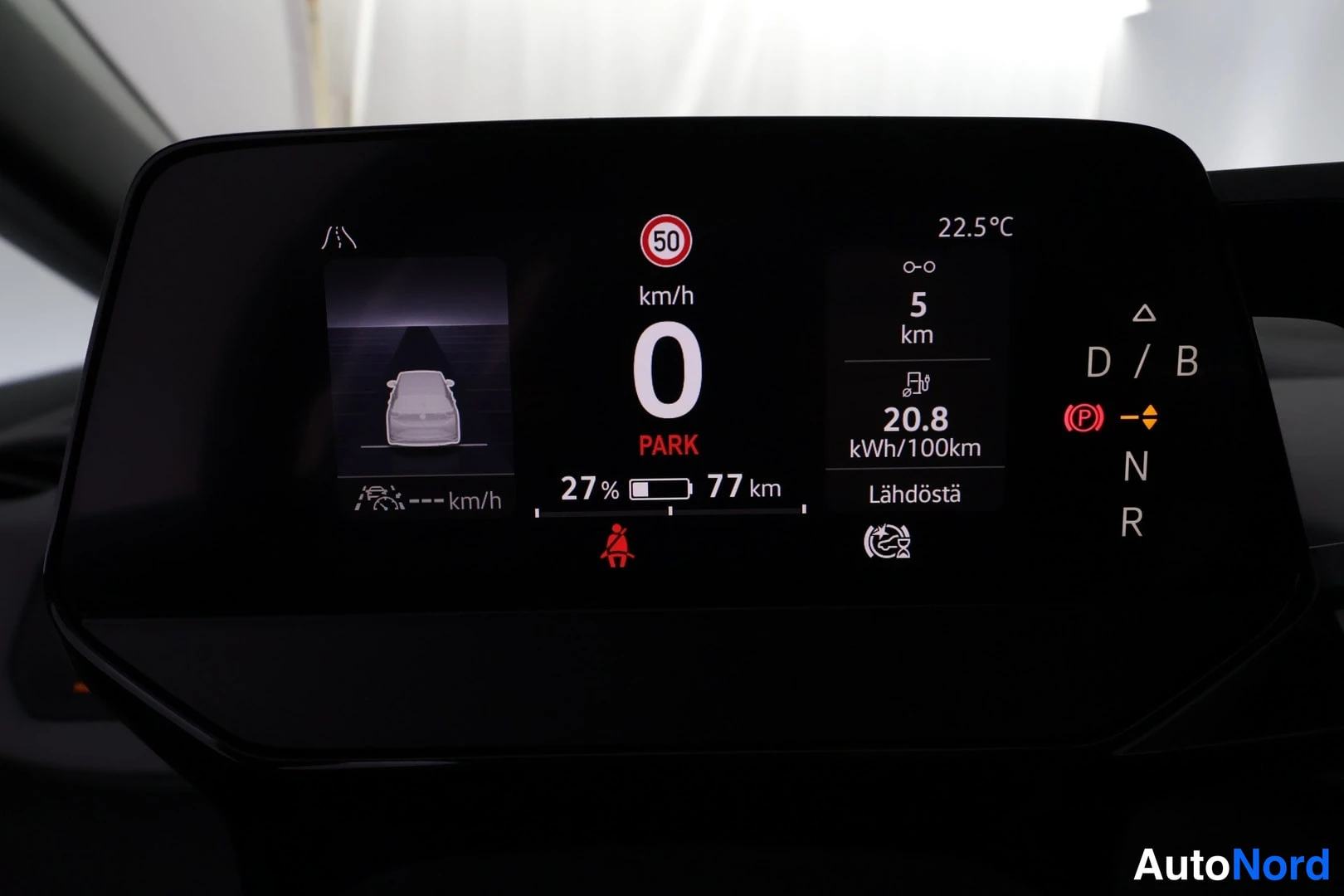 Muu: Kojelaudan digitaalinen mittaristo: nopeus 0 km/h, PARK, akun varaus 27 %, toimintamatka 77 km, kulutus 20,8 kWh/100 km, matka 5 km, lämpötila 22,5 °C.
