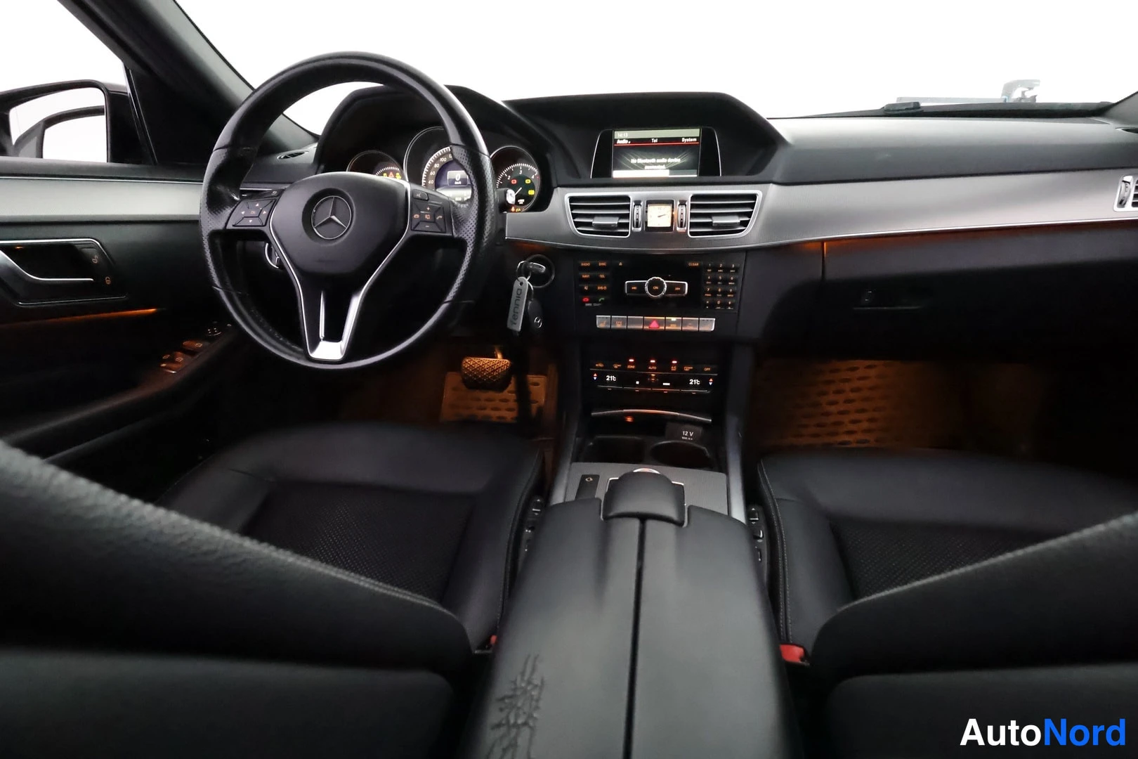 Yksityiskohta: Ohjaamon yleiskuva: ohjauspyörä, mittaristo, keskikonsoli ja etuistuimet mustalla verhoilulla.