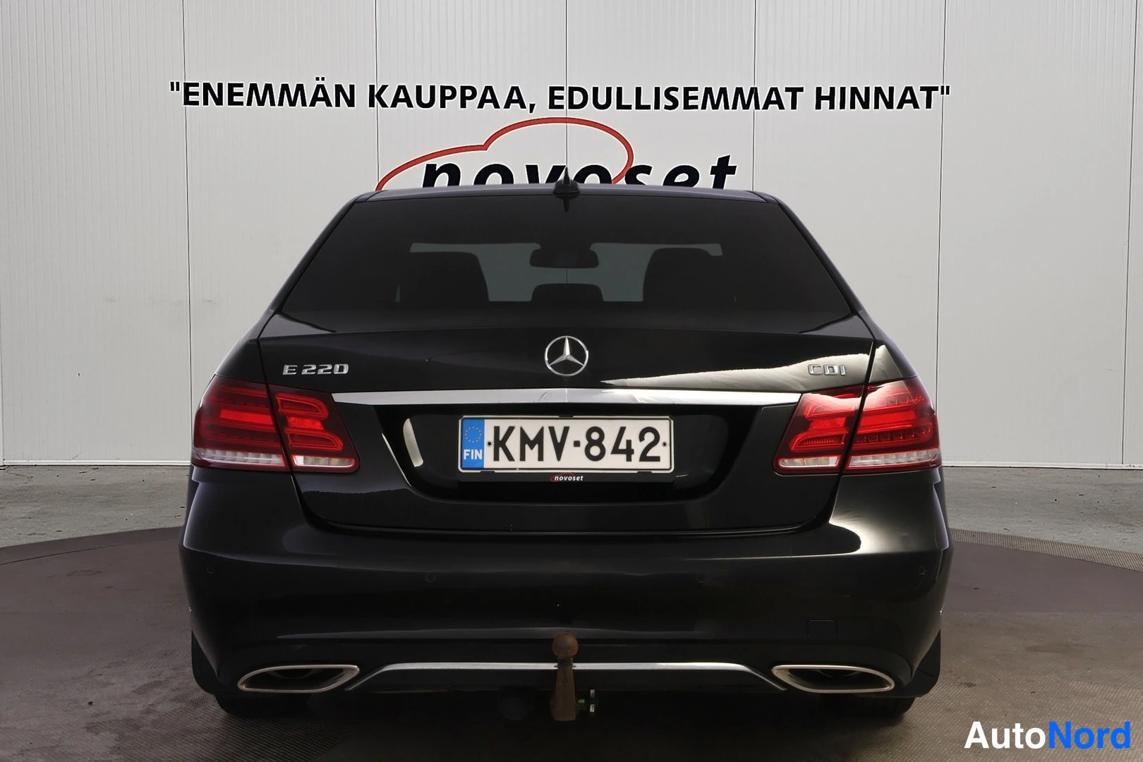 Takaa: Mustan sedanin takaosa suoraan takaa: E 220- ja CDI-merkit, takavalot, rekisterikilpi ja vetokoukun pallo puskurin alla.