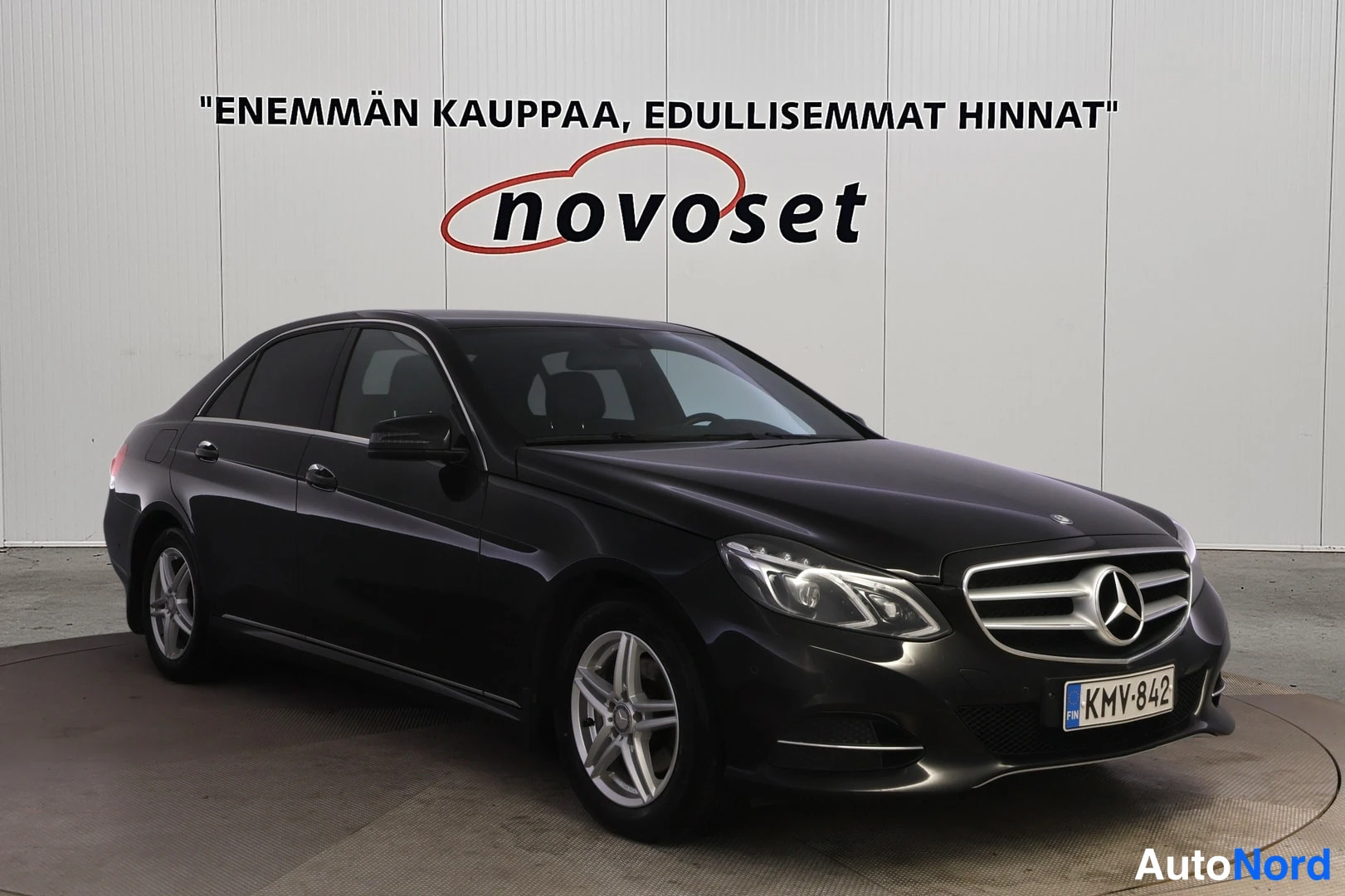 Etuviisto, nokka oikealle: Mustan Mercedes-Benzin etukulmanäkymä, etusäleikkö ja rekisterikilpi näkyvät oikealla.
