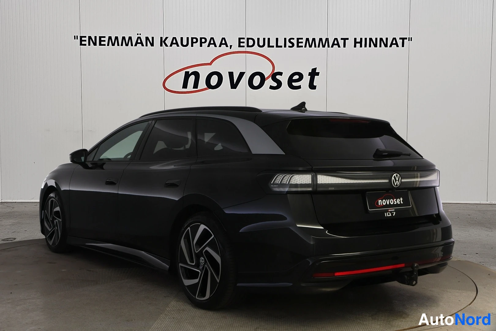 Takaviisto: Mustan farmariauton takaviisto, jonka perä on kuvan oikeassa laidassa. Näkyvät pitkä poikittainen takavalo, VW-merkki, novoset-kyltti rekisterikilven paikalla j