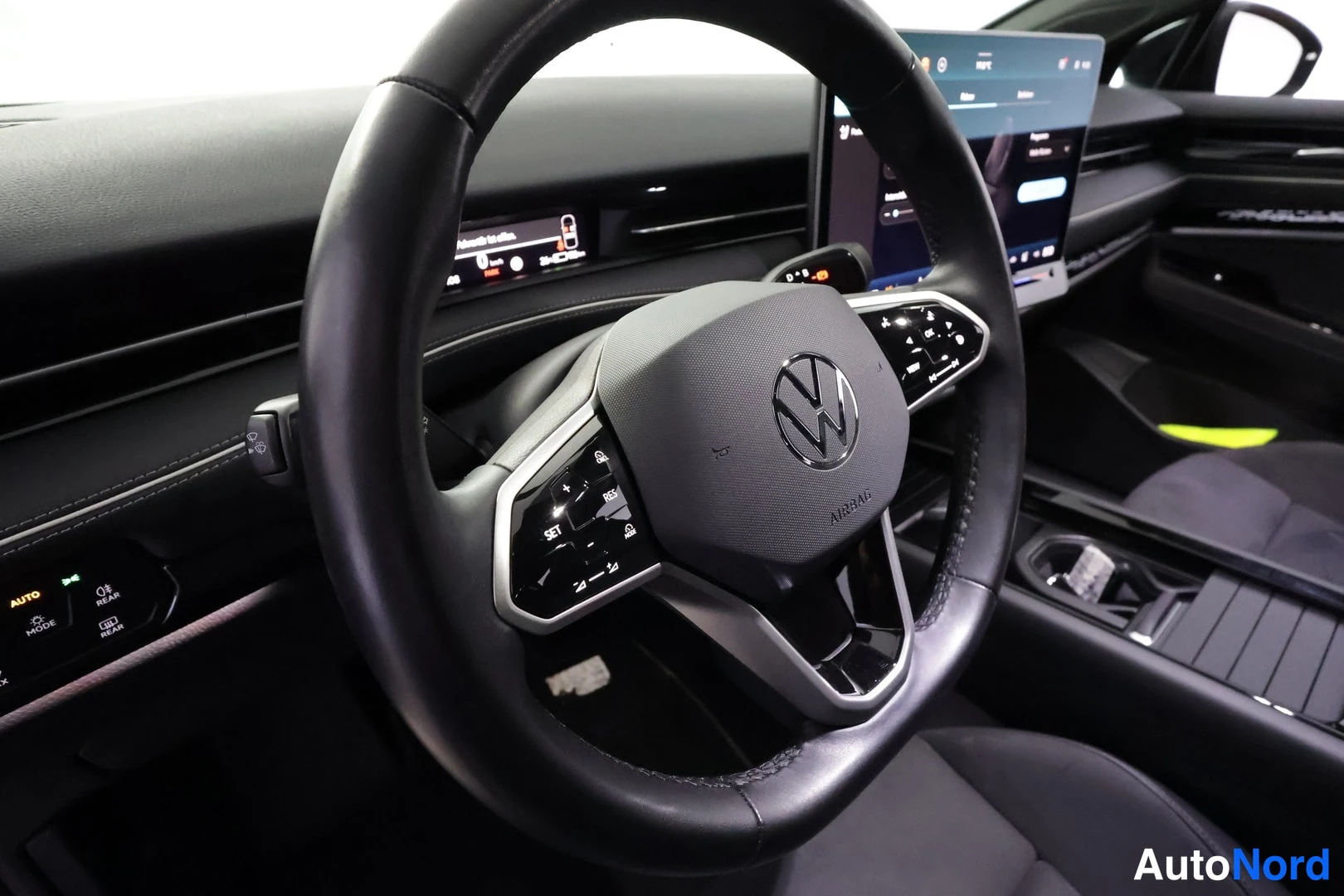Muu: Volkswagenin ohjaamon sisäkuva: musta multitoimiohjauspyörä VW-tunnuksella, suuri kosketusnäyttö ja tumma mittaristonäyttö.