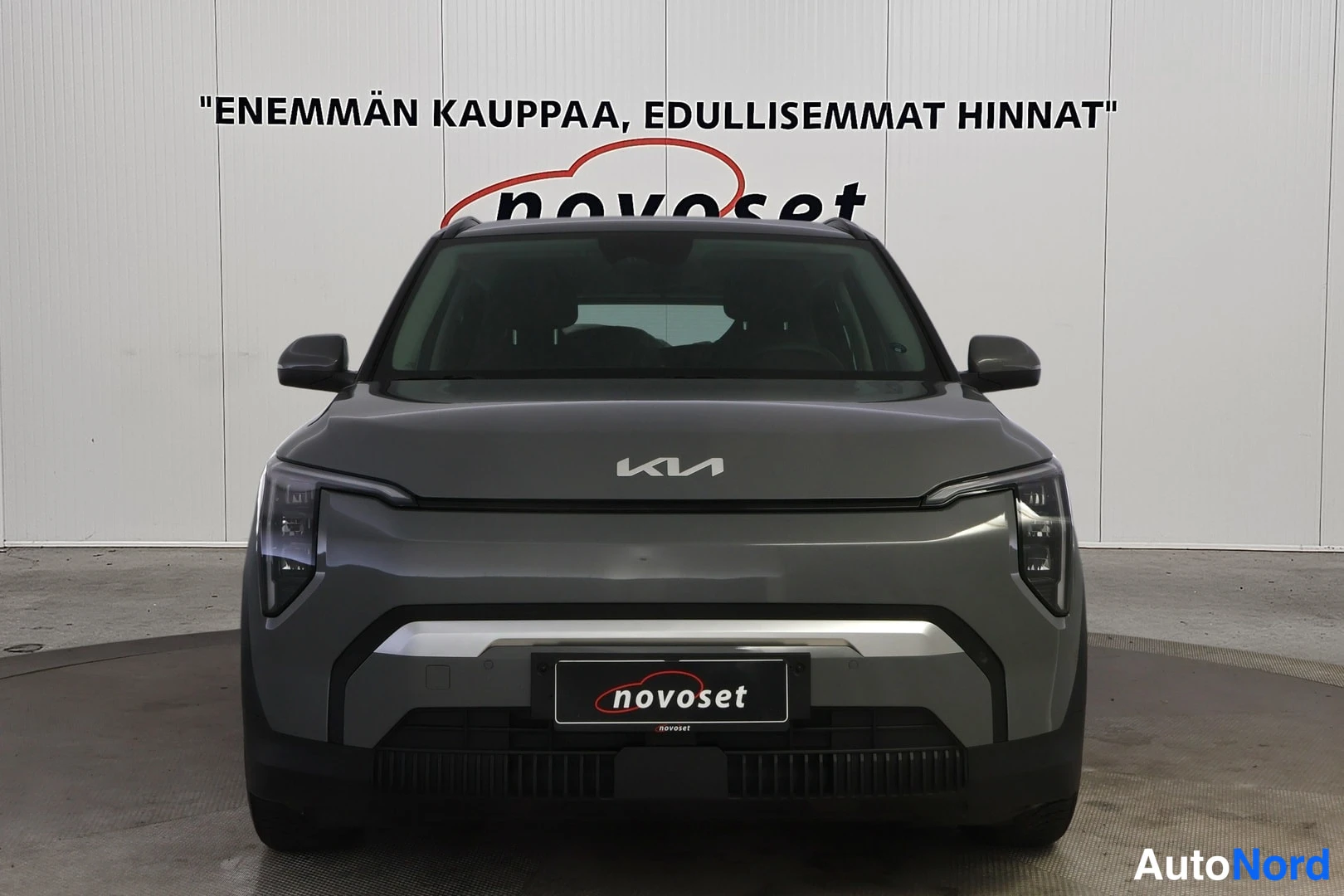Edestä: Kia EV3 suoraan edestä kuvattuna; KIA-merkki konepellissä ja novoset-teksti rekisterikilven paikalla etupuskurissa.