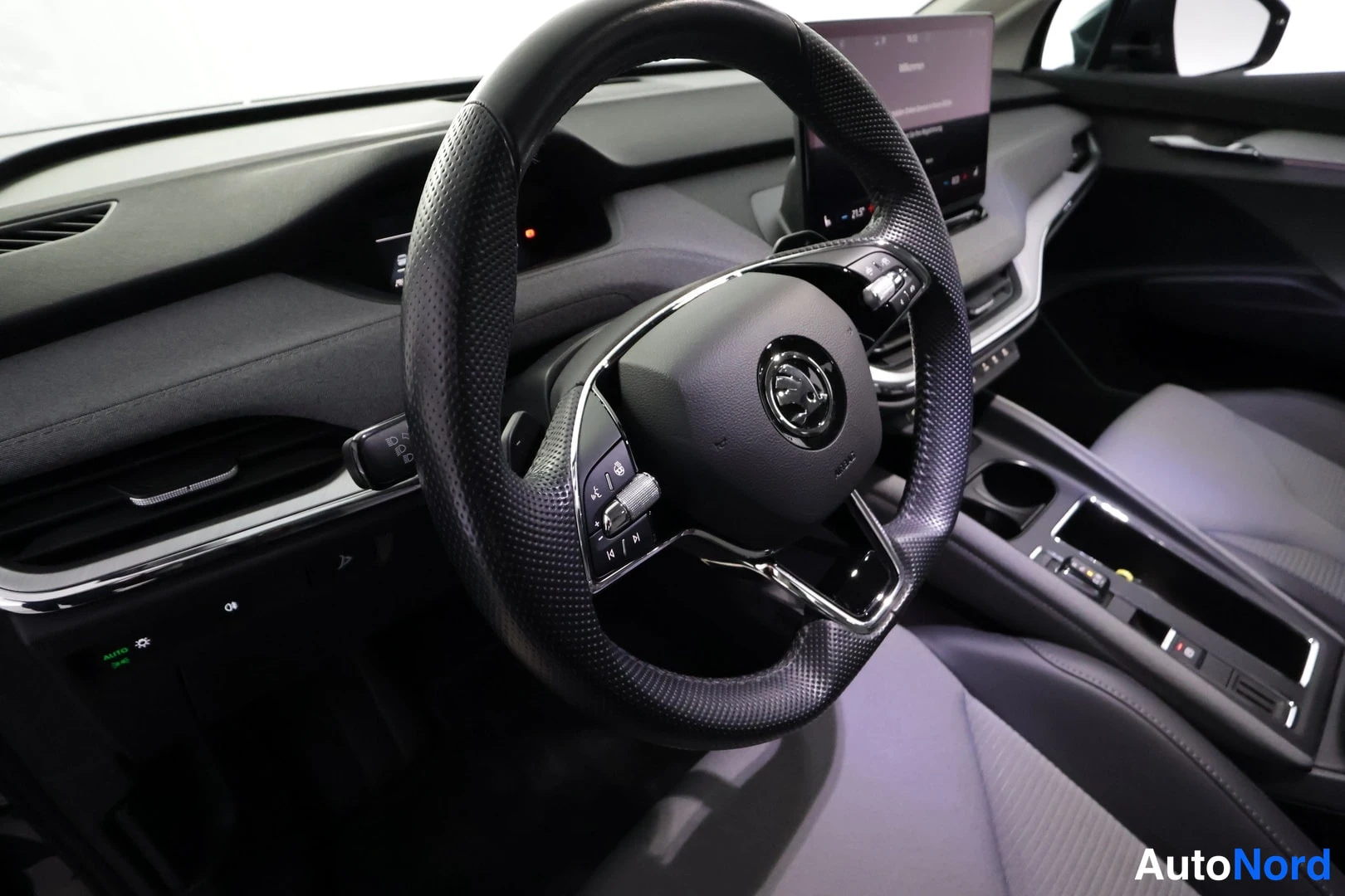 Muu: Kuljettajan näkökulma Skoda-ohjauspyörään ja infotainment-näyttöön, jossa on lisätty hallintapaneeli ja säätöohjaimet.