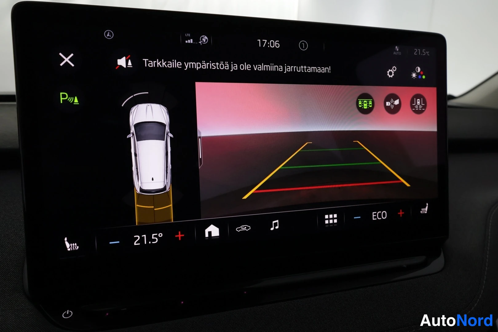 Muu: Infotainment-näyttö, jossa taaksepäin kääntyvä kamera kuva kaistaviivoilla ja varoitusviesti.