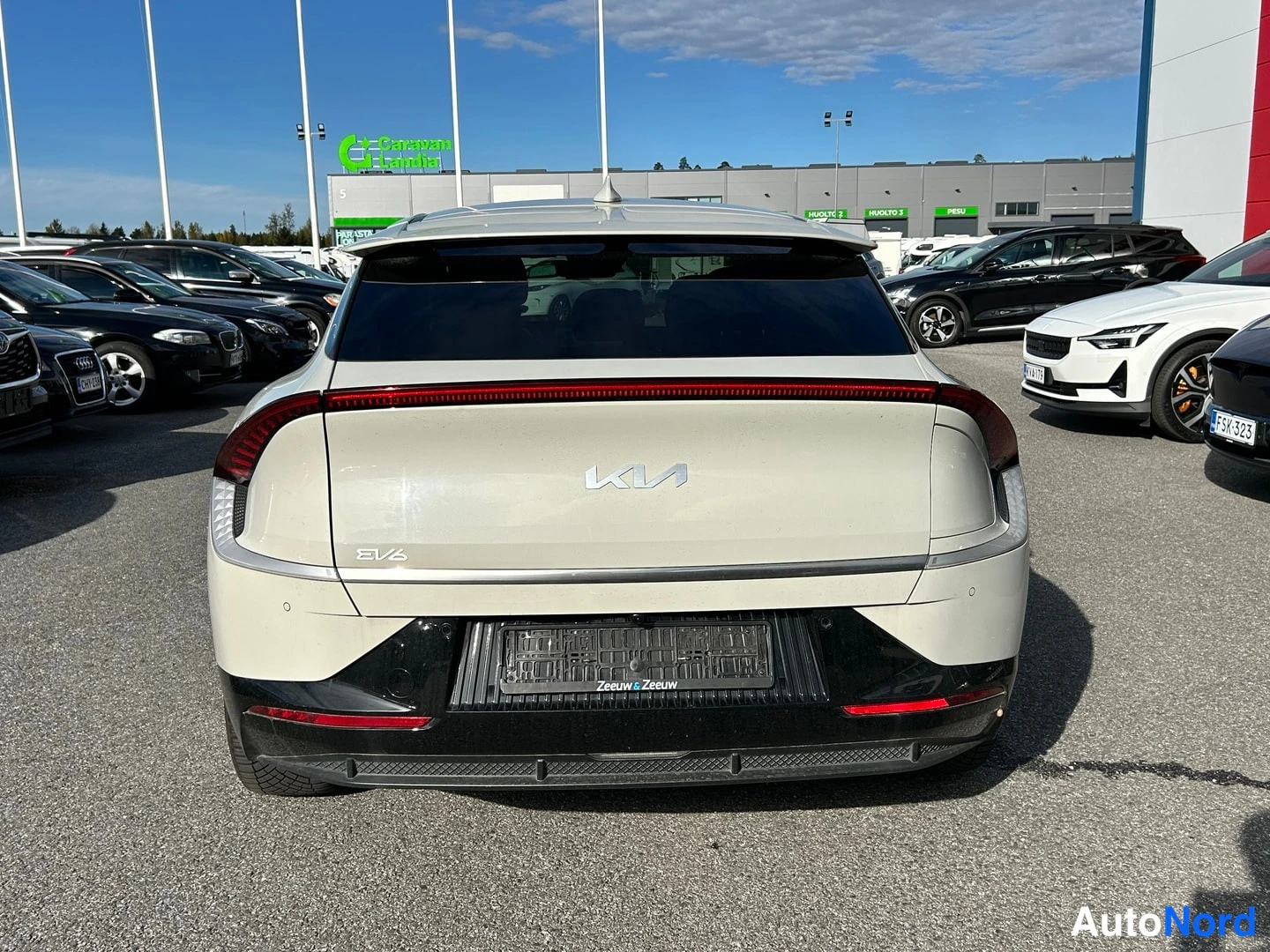 Takaa: Kia EV6:n perä suoraan takaa kuvattuna; poikittainen takavalo ja EV6-merkki näkyvät, rekisterin paikan alla Zeeuw & Zeeuw -teksti, ympärillä parkkipaikan muita