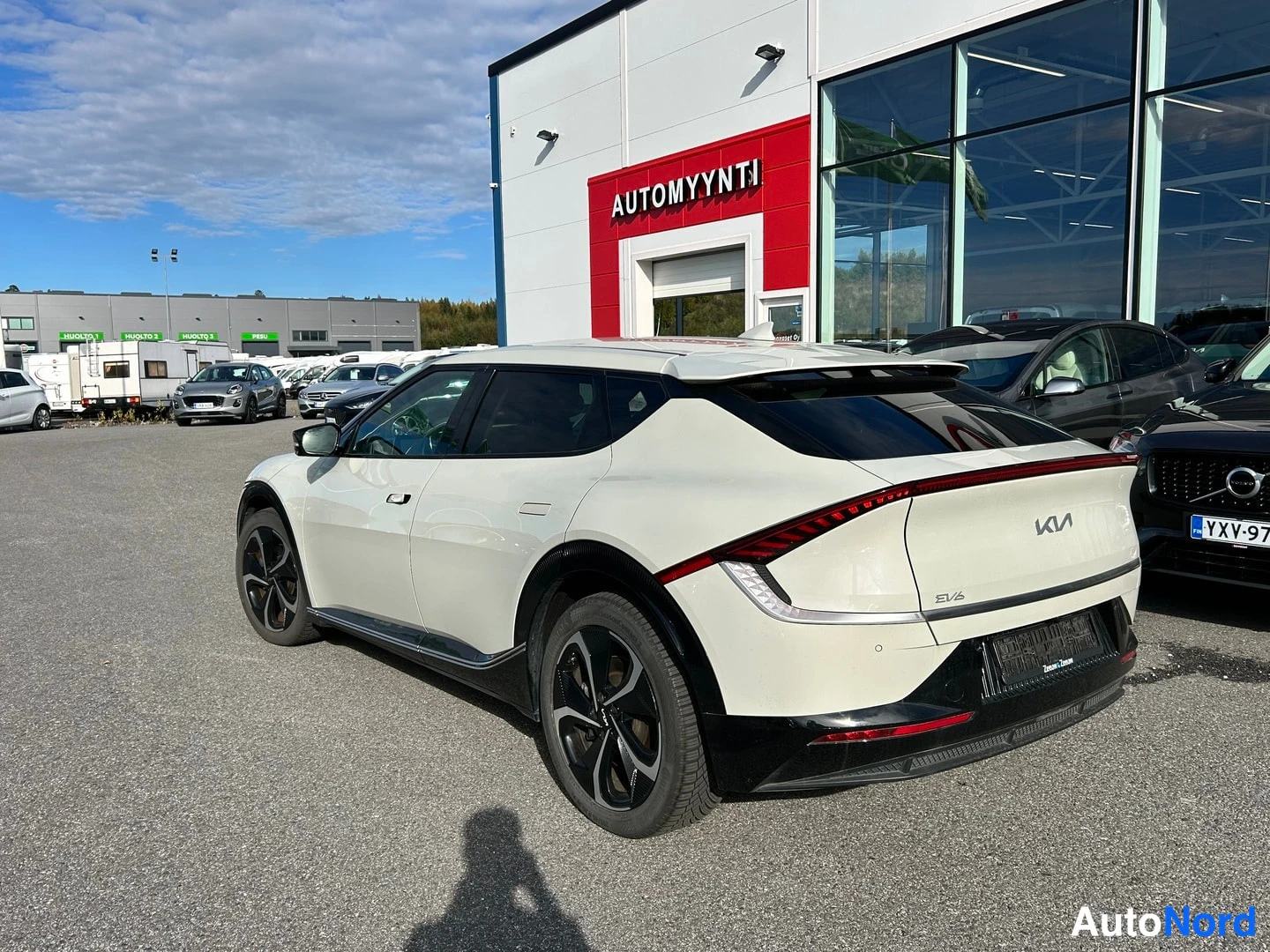 Takaviisto: Kia EV6 takaa kulmasta kuvattuna valkoisena autoliikkeen pihalla.
