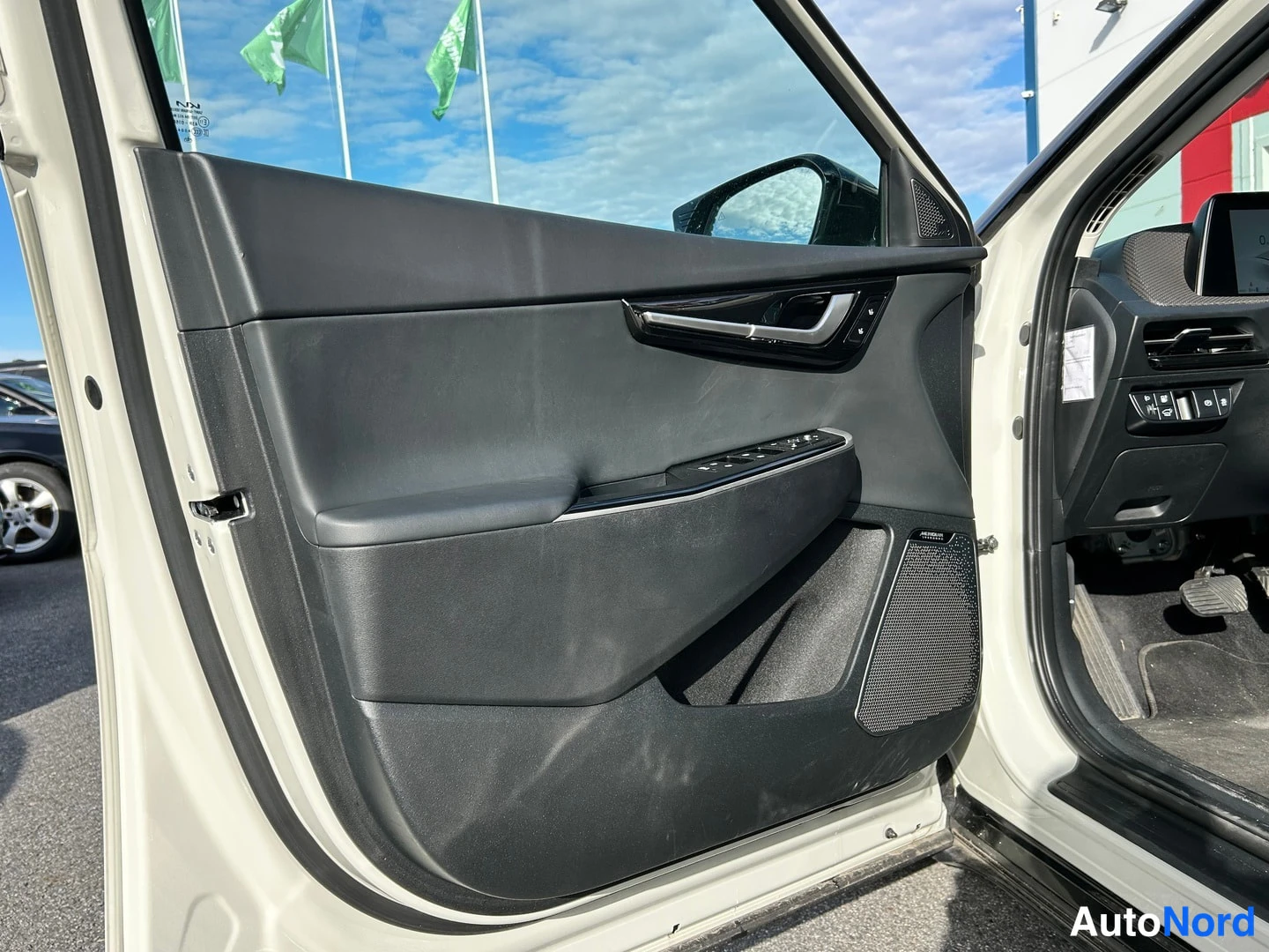 Sivulta: Autojen sisätiloja, avattu etuoven paneeli Harman Kardon -kaiuttimella ja ikkunankytkimillä.