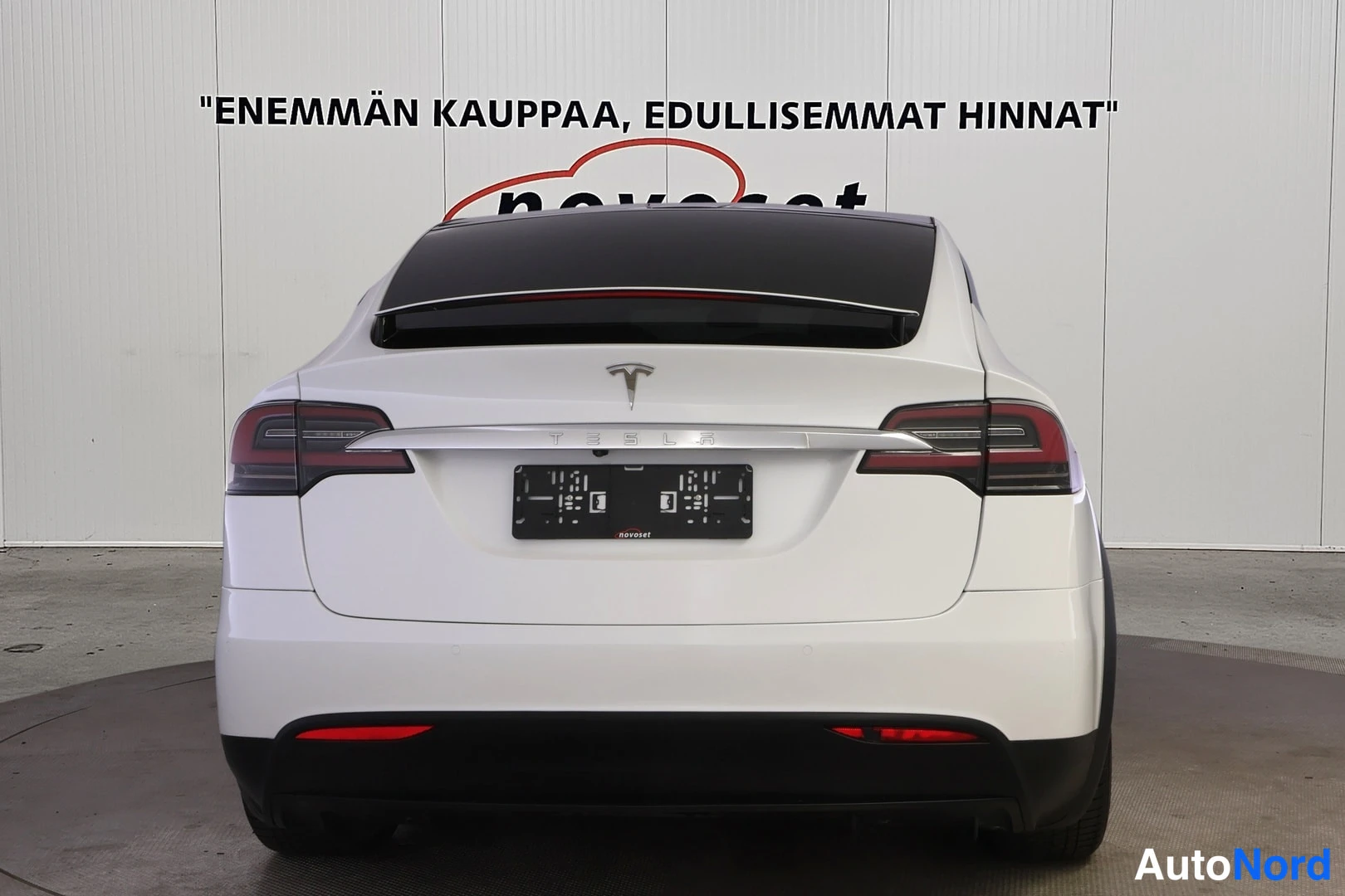 Takaa: Valkoisen Tesla Model X:n perä suoraan takaa kuvattuna: T-merkki ja TESLA-kirjaimet takaluukussa, tummat takavalot, tumma lasikatto ja musta puskuri.