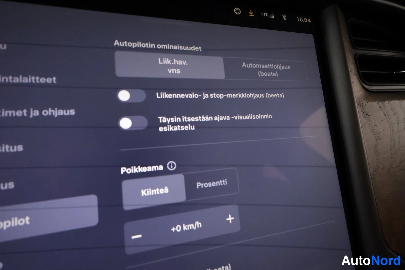 Muu: Auton kesk Näytön Autopilotin ominaisuudet -valikko, jossa liikennevalo- ja stop-merkkiohjaus sekä polkema-asetus Kiinteä +0 km/h.