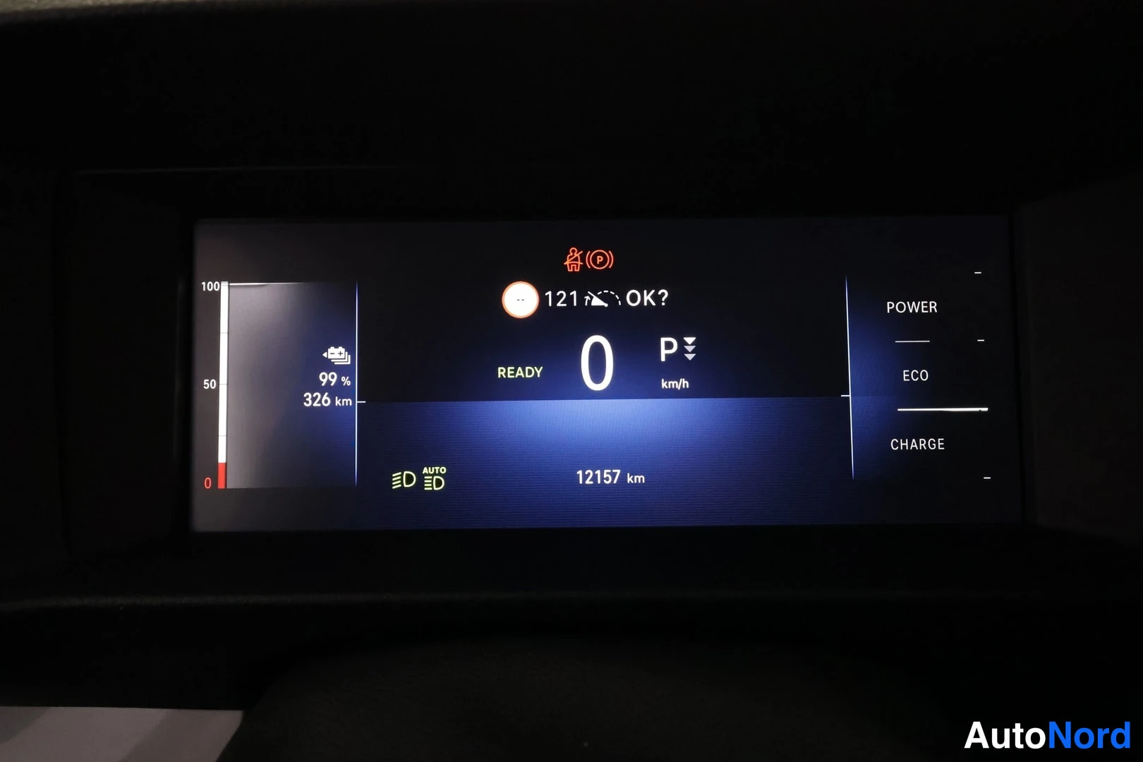 Yksityiskohta: Kojelaudan näyttö: valmiustila READY, 0 km/h, akun varaus 99 %, toimintamatka 326 km, matkamittari 12157 km.
