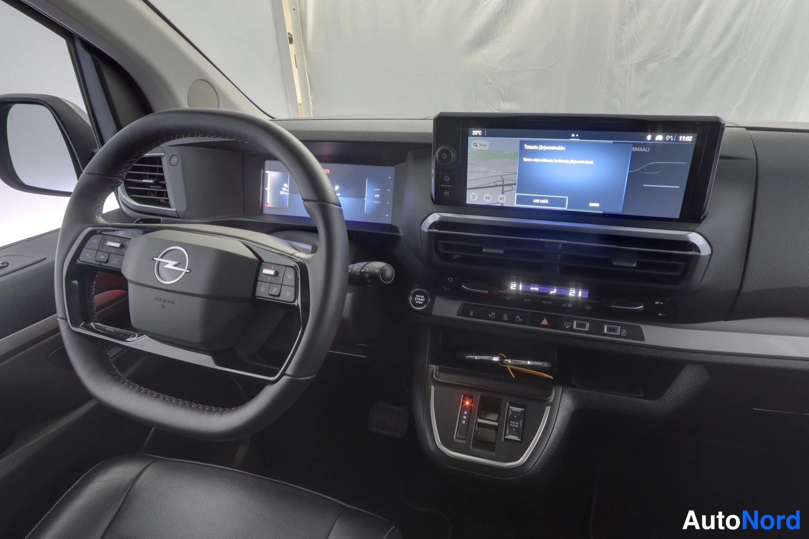 Yksityiskohta: Lähikuva ohjaamon kojelaudasta: Opel-ohjauspyörä, digitaalinen mittaristo, infotainment-näyttö ja vaihinsäätimet.