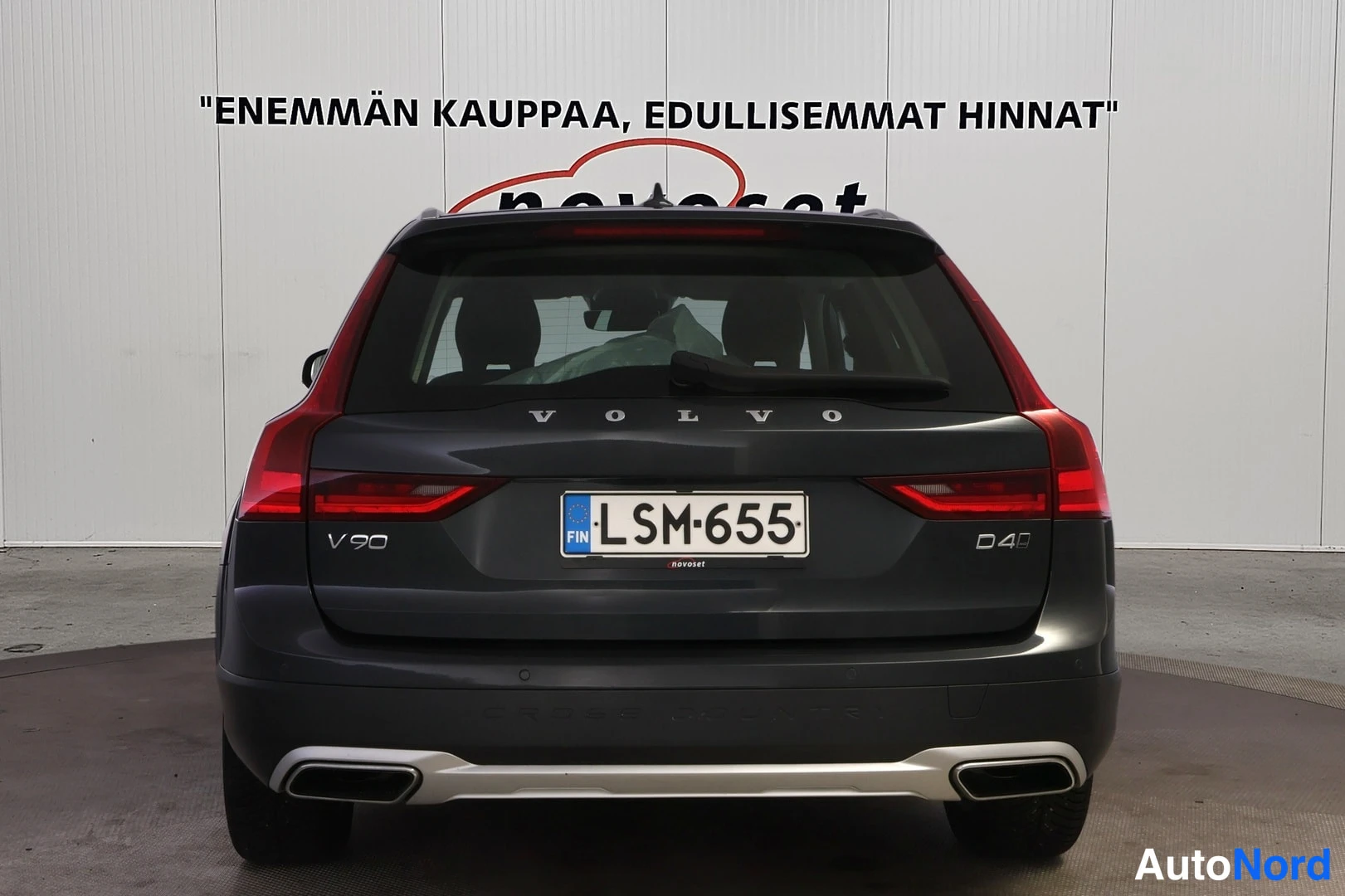 Takaa: Tummanharmaan farmariauton takaosa suoraan takaa, VOLVO-teksti, V90- ja D4-merkinnät sekä rekisterikilpi.