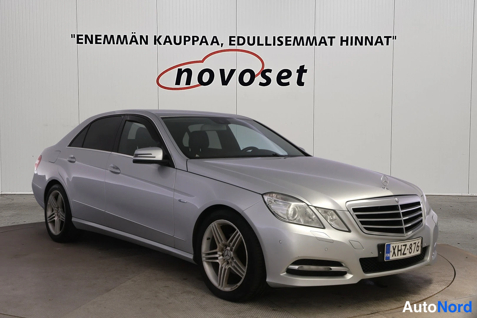 Etuviisto, nokka oikealle: Hopeinen Mercedes-Benz-sedan etuviistosta oikealta kuvattuna: keulagrilli, ajovalot ja vasen kylki näkyvät, rekisterikilpi.