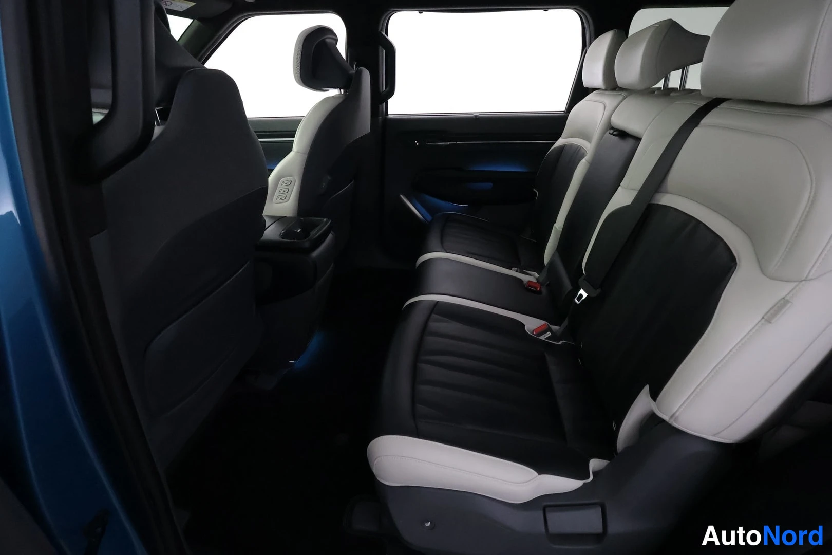 Muu: Auton sisätila oikealta sivulta: kaksivärinen (mustavalkoinen) takaistuin, etuistuimen selkänoja ja takimmainen ovi auki.