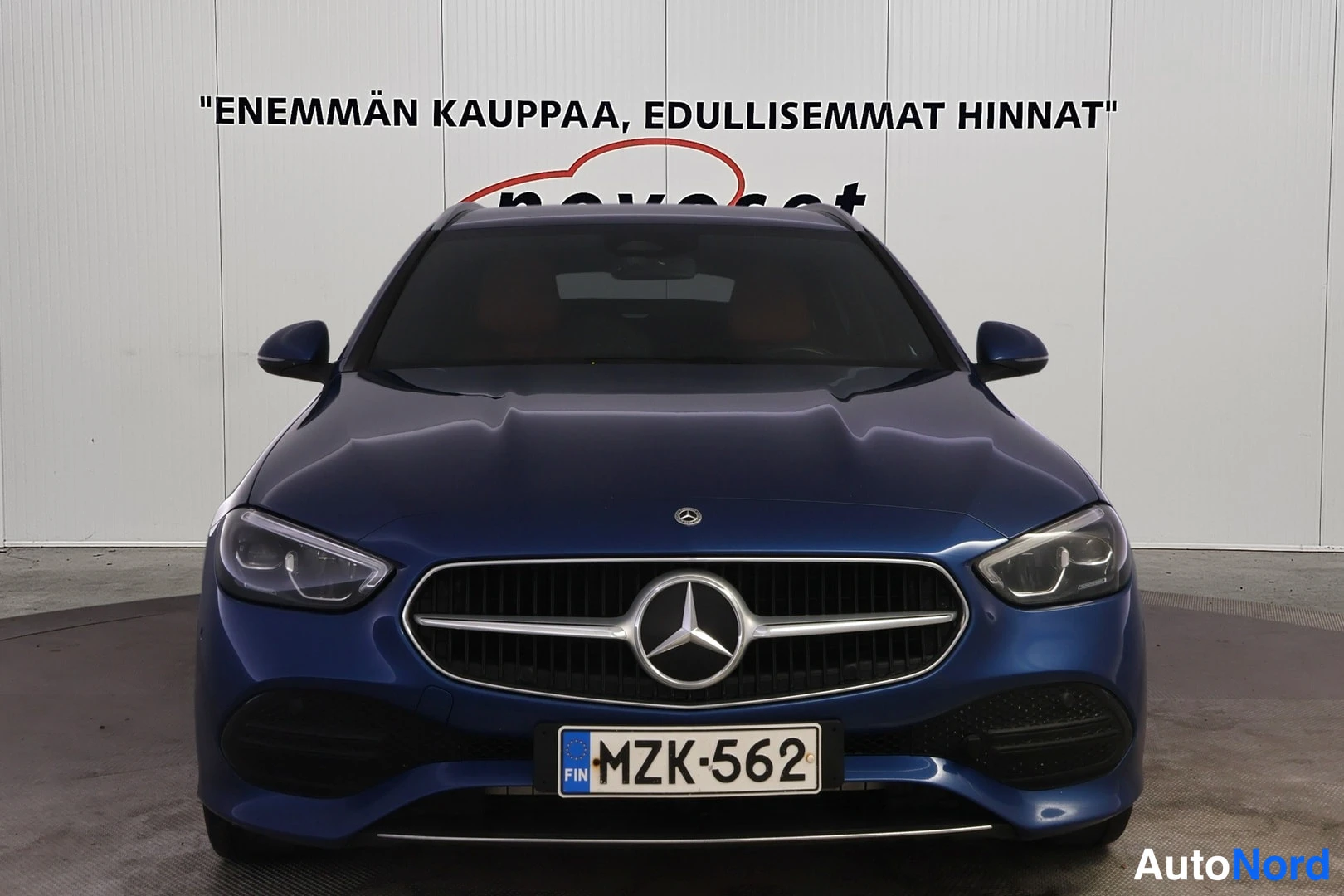 Edestä: Direct front view of a blue car showing the chrome grille with the Mercedes-Benz star logo, license plate reading, and LED headlights.