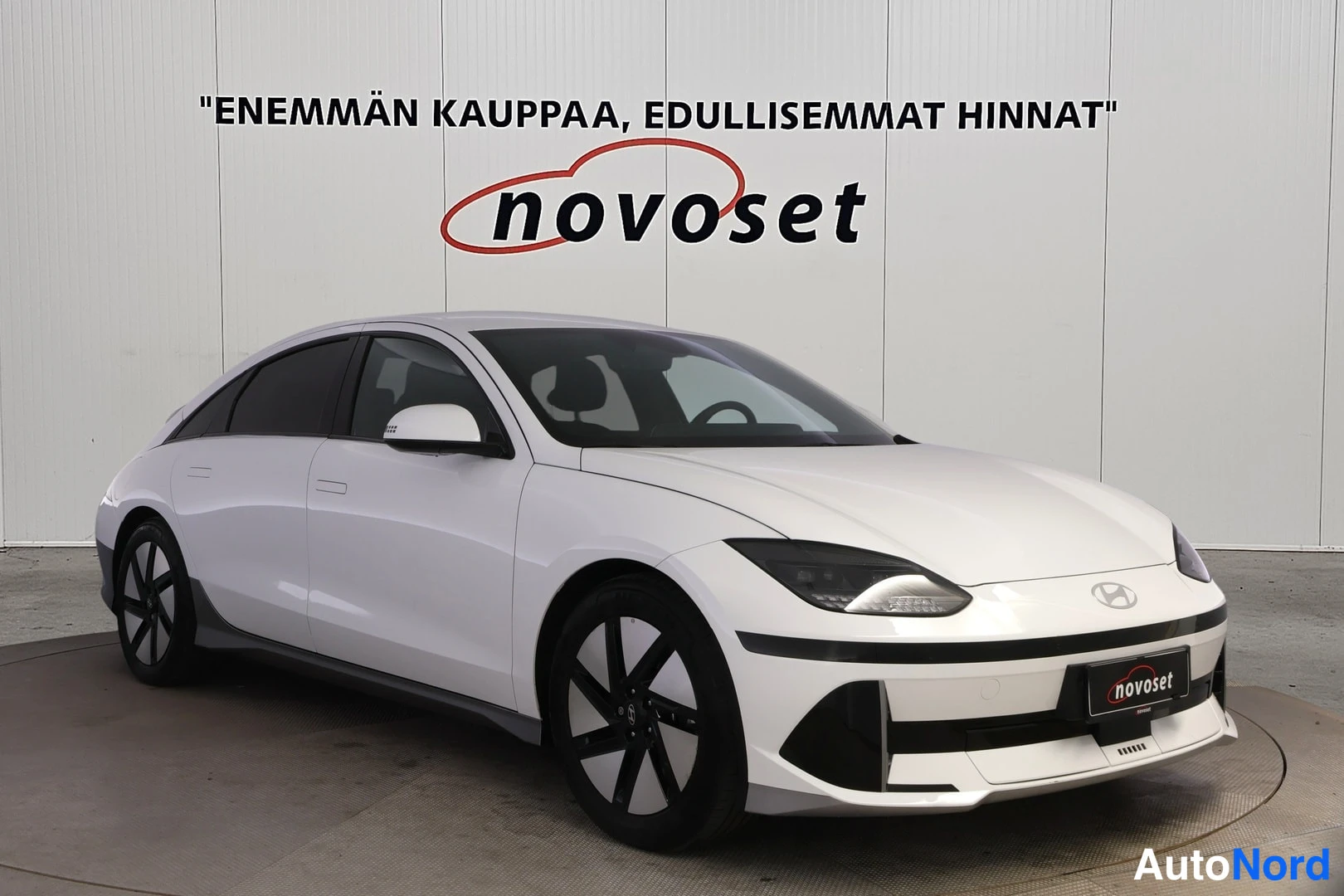 Etuviisto, nokka oikealle: Hyundai IONIQ 6 front three-quarter view, white body, photographed indoors.