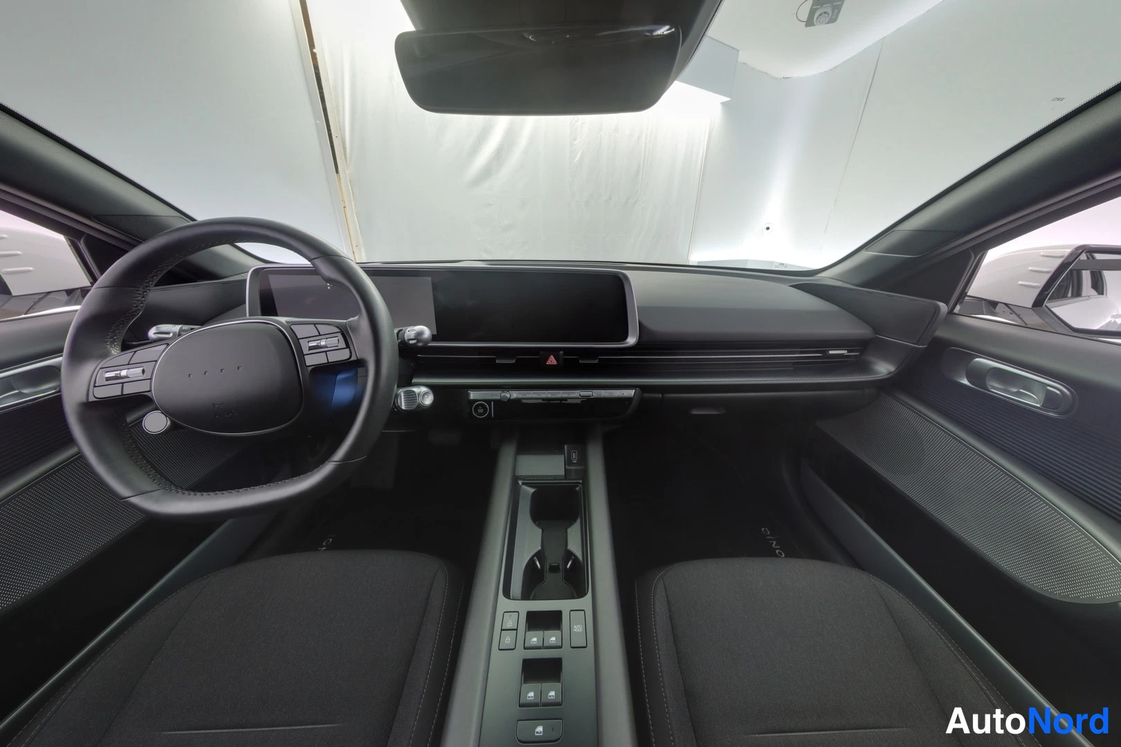Muu: Hyundai IONIQ 6 cockpit view showing steering wheel, wide dashboard screen and black seats.