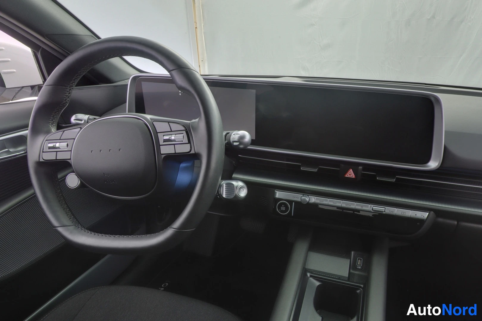 Muu: Hyundai IONIQ 6 steering wheel and dashboard close-up with large curved display.