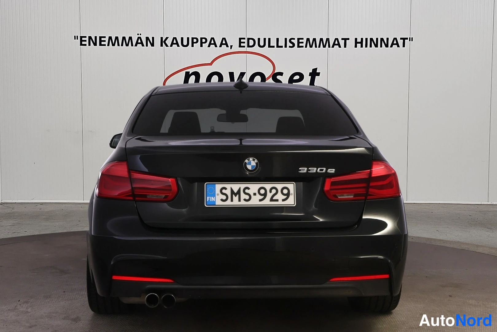 Takaa: Musta BMW-henkilöauto suoraan takaa kuvattuna, takaluukussa 330e-merkintä, rekisteritunnus.