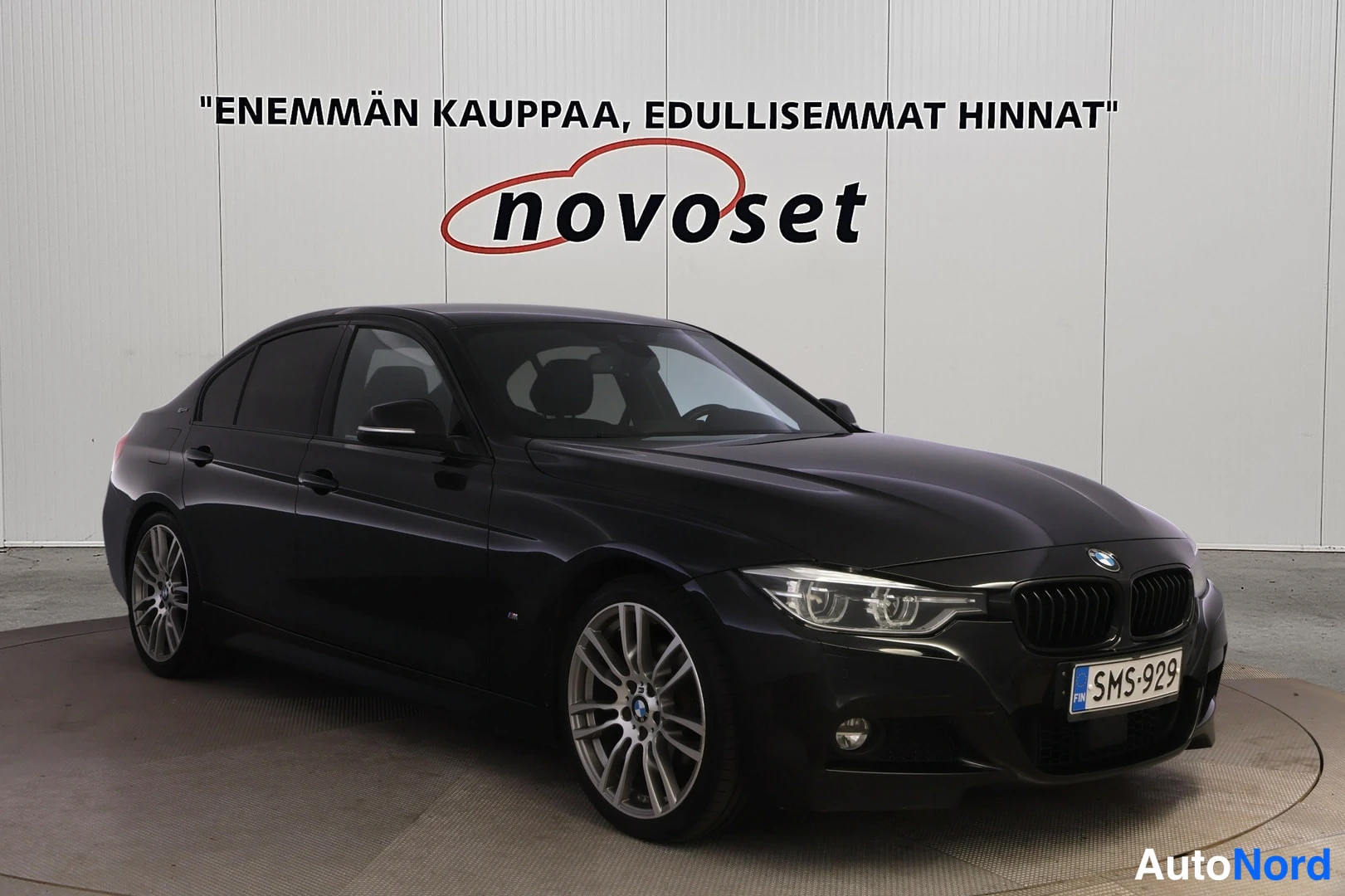 Etuviisto, nokka vasemmalle: Musta neliovinen BMW-sedan kuvattuna etuviistosta kulmasta (grilli vasemmalla kuin takapyörä)