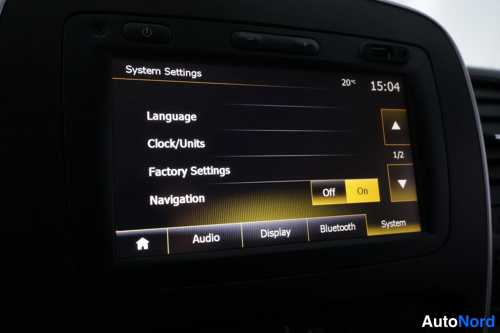 Yksityiskohta: Infotainment-näytön System Settings -valikko, jossa asetuksina Language, Clock/Units, Factory Settings ja Navigation; oikealla yläkulmassa kello 15:04 ja lämpöt
