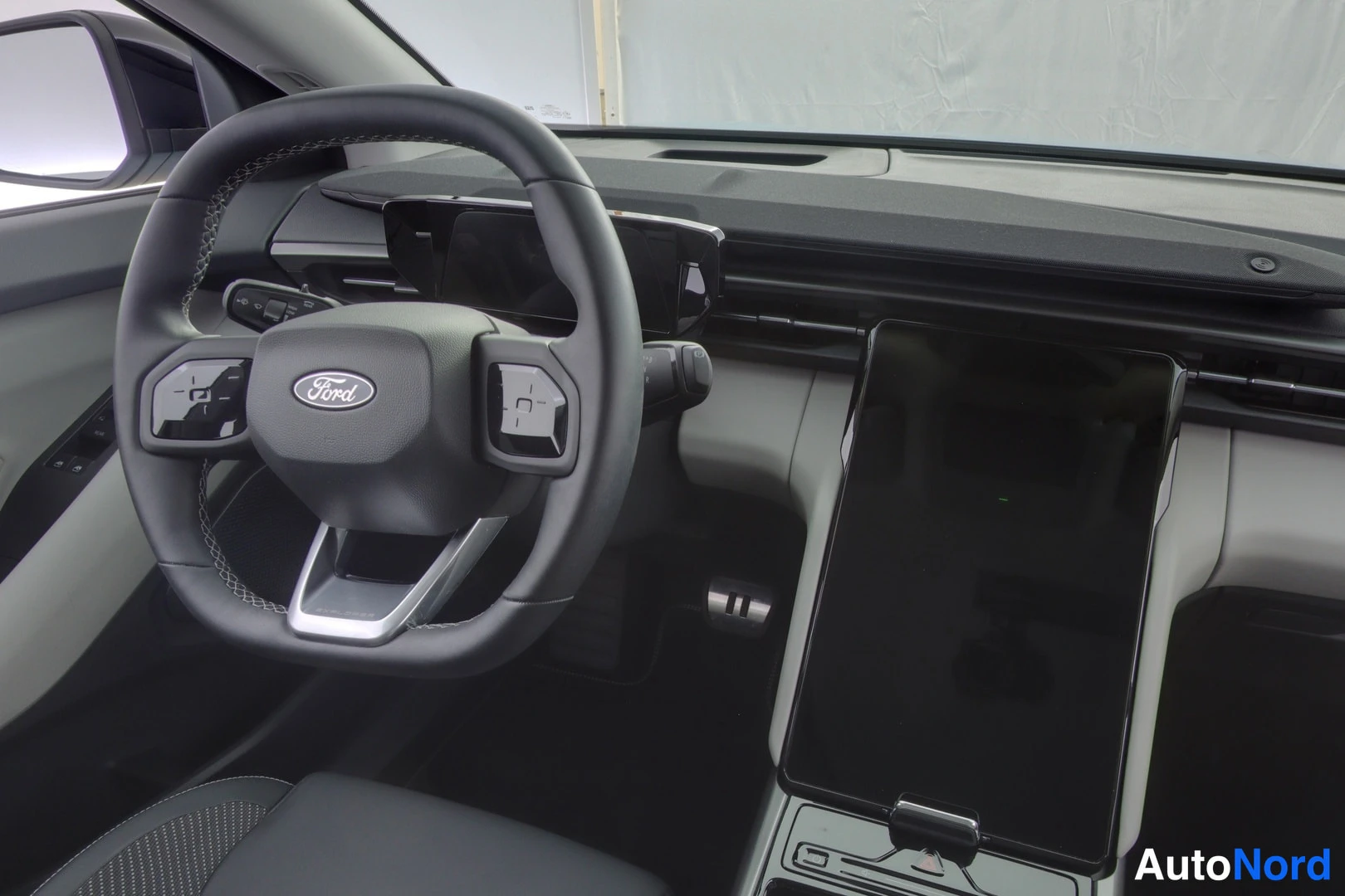 Etuistuimet: Close-up of driver area showing multi-function steering wheel with Ford emblem, digital instrument panel, large vertical centre touchscreen and centre console c