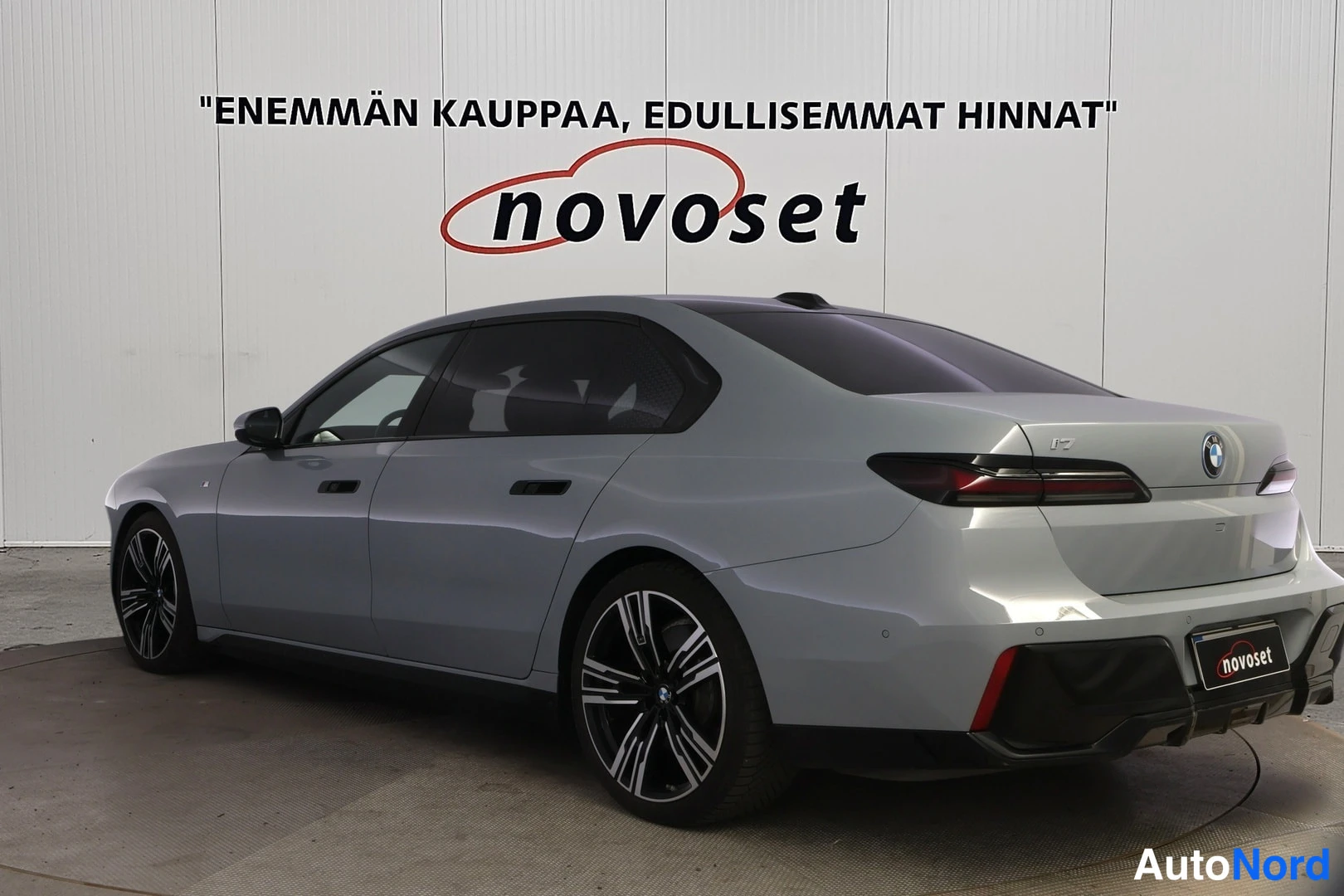 Takaviisto: Harmaa BMW i7 -sedan takakulmasta: takavalo, boot-kannella i7-merkintä ja BMW-merkki sekä vasen kylki ja tummat kevytmetallivanteet näkyvät.