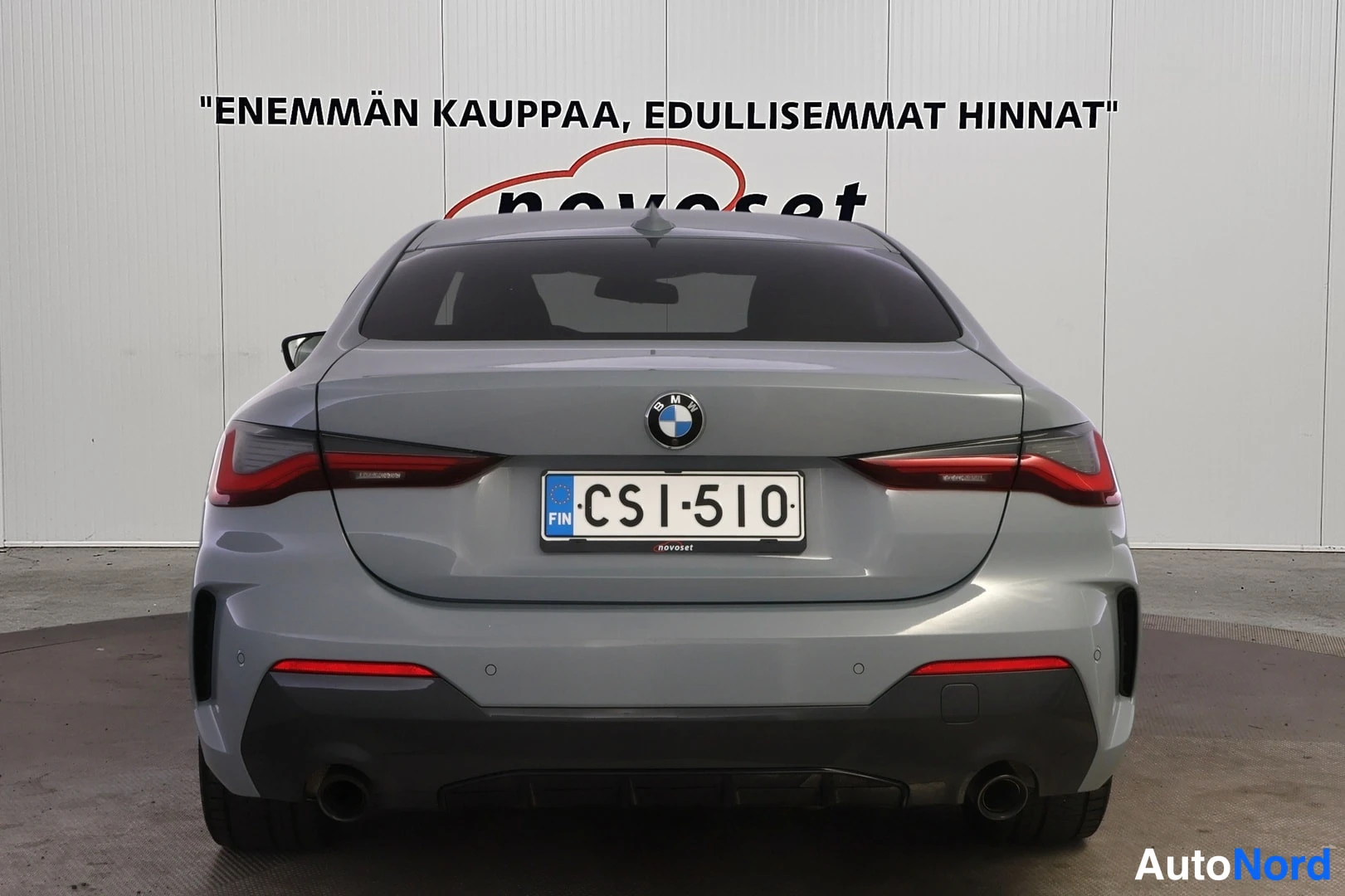 Takaa: Harmaa BMW-coupé suoraan takaa kuvattuna; BMW-merkki takaluukussa, tummennetut takavalot, kaksi pakoputkea, rekisterikilpi.