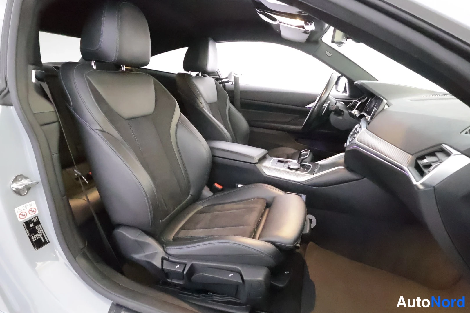 Muu: Auto from inside showing black front seats, dashboard and steering wheel viewed from the open driver's side door.