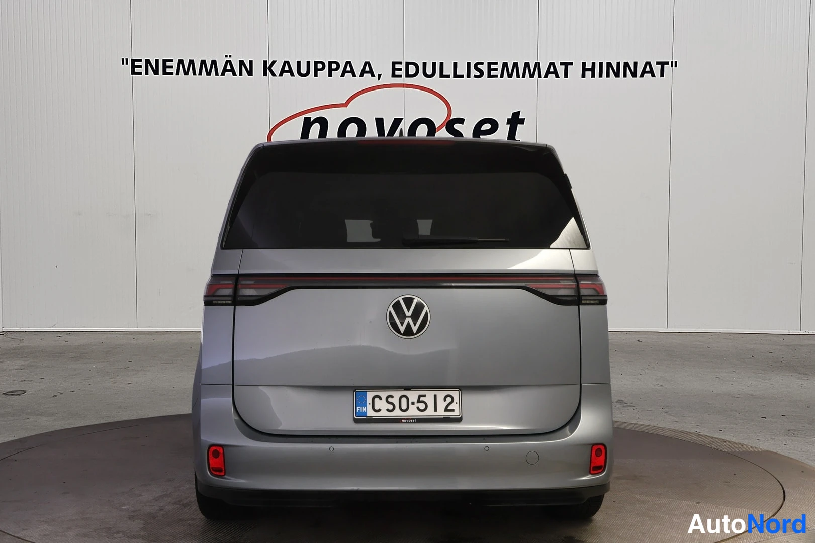 Takaa: Direct rear view of the silver-grey van with full-width LED tail light strip across the tailgate, central VW emblem and Finnish license plate
