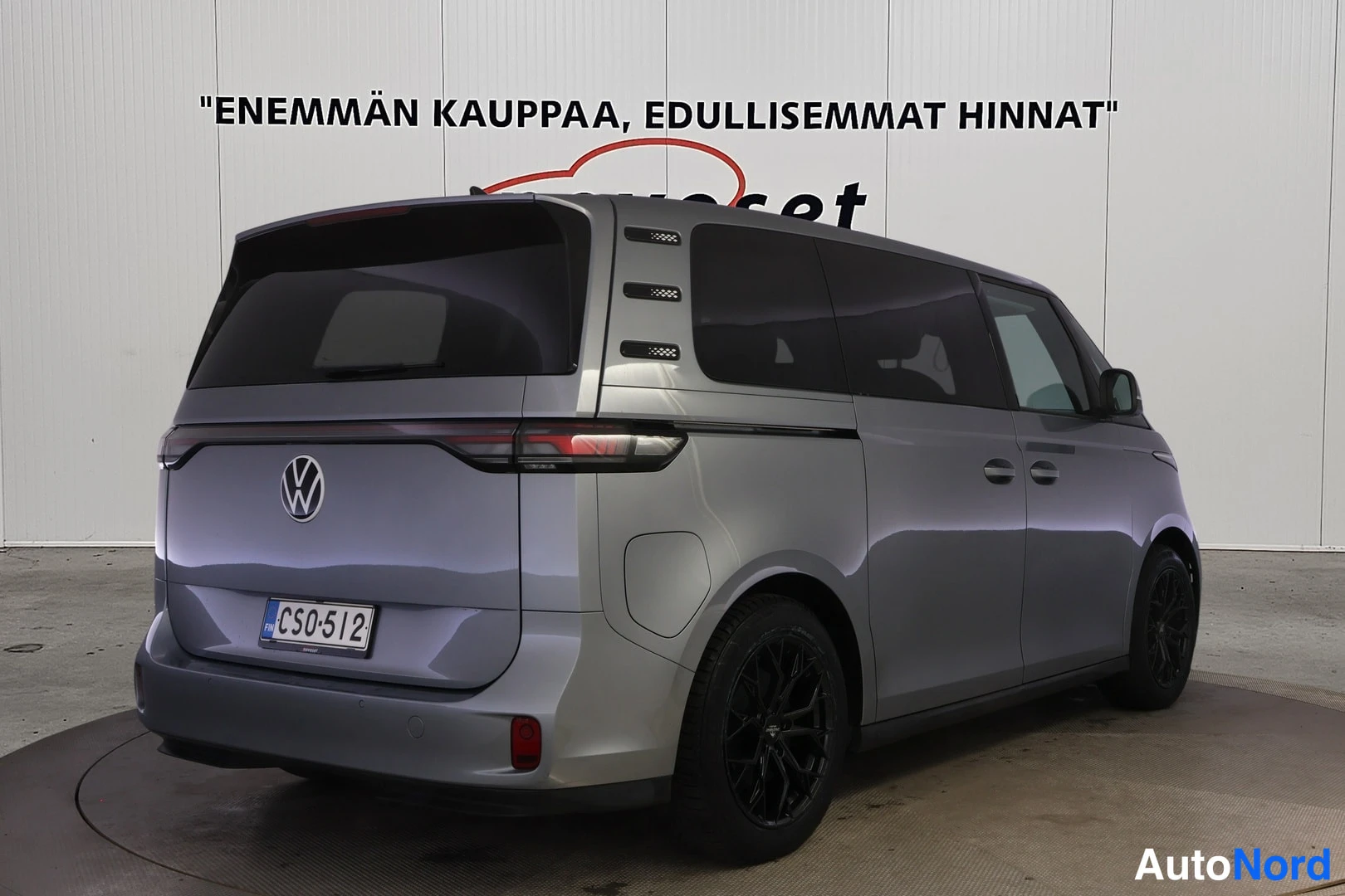 Takaviisto: Volkswagen ID. Buzz in metallic grey photographed from rear three-quarter angle displaying right-side profile, black alloy wheels and sliding door handle
