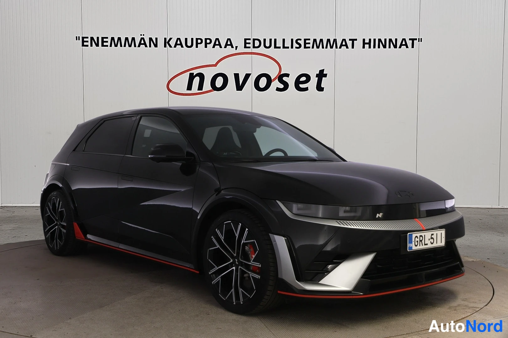 Etuviisto, nokka oikealle: Mustan hatchbackin etukulma vasemmalta edestä, tummat vanteet ja punaiset jarrusatulat näkyvät.