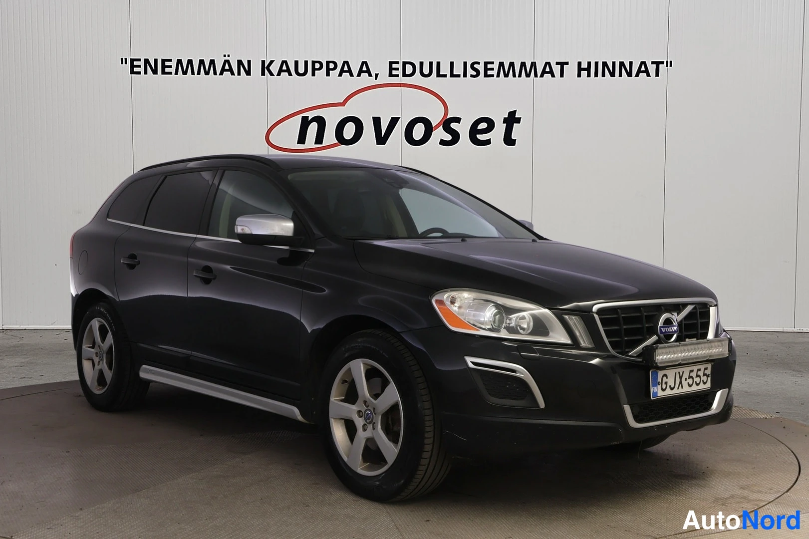 Etuviisto, nokka oikealle: Musta Volvo XC60 etukulmasta oikealta, metallinen jäähdinritilä ja tehopajut etupuskurissa.