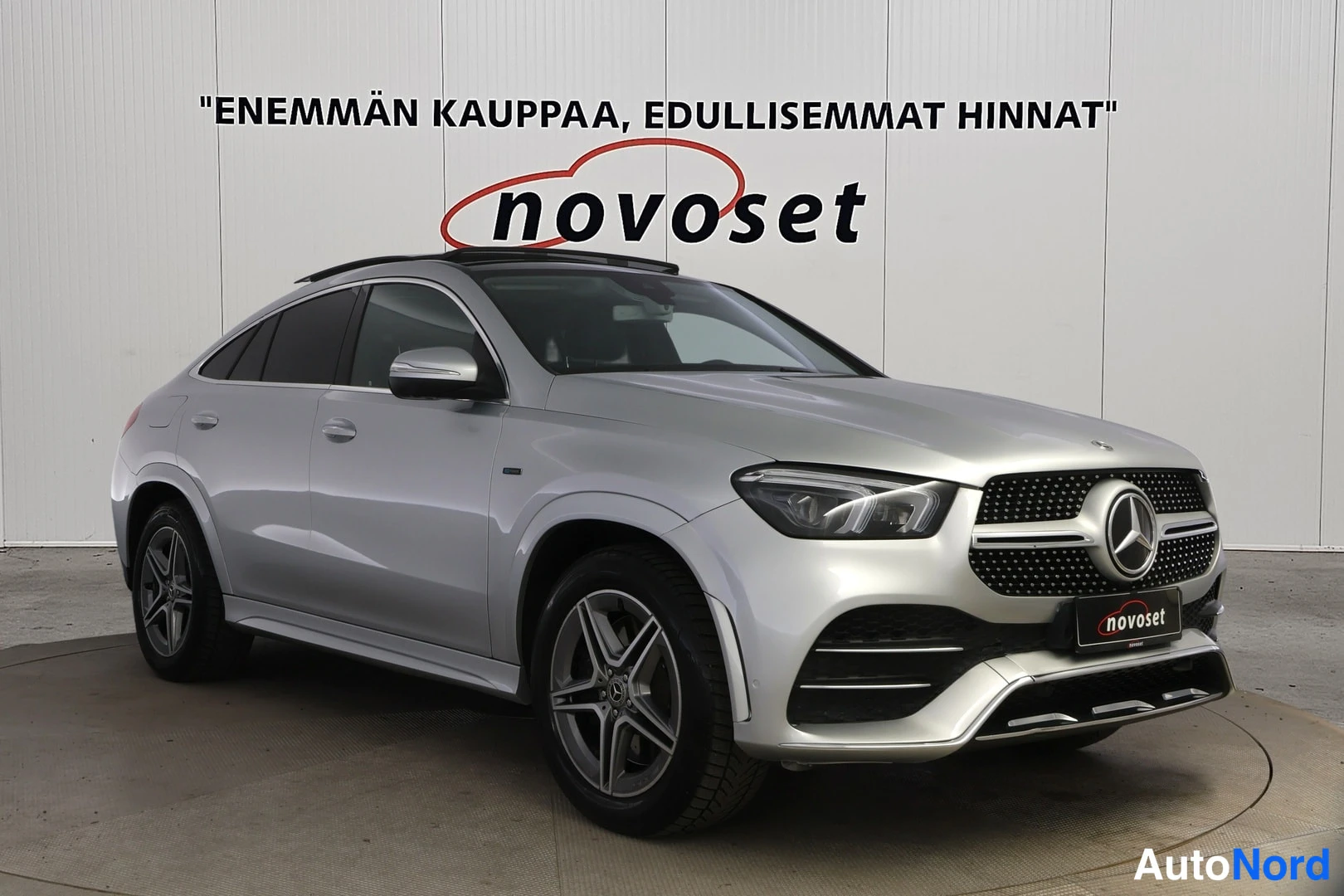 Etuviisto, nokka oikealle: Hopeinen Mercedes-Benz GLE Coupé kolmineljäyksestä edestä ja vasemmalta sivulta sisätiloissa.