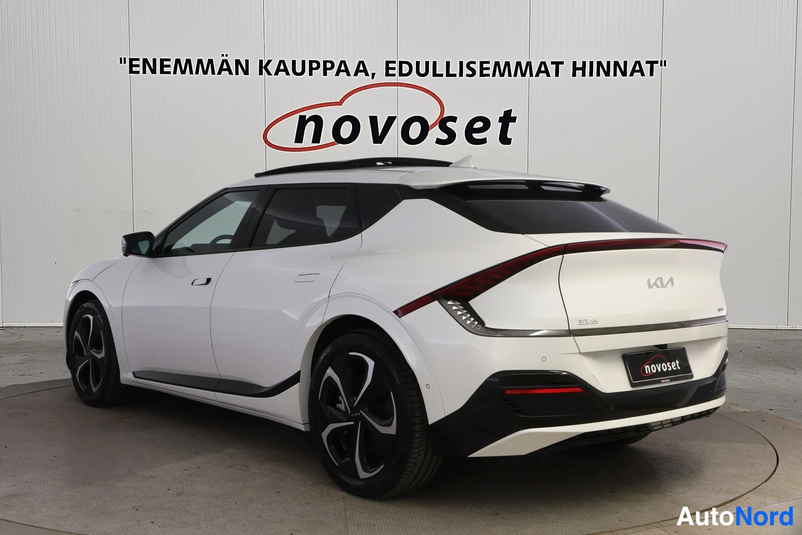 Takaviisto: Valkoinen Kia EV6 takavasemmalta kuvattuna, GT-ratkaisu näkyvissä takaoven paneelissa.
