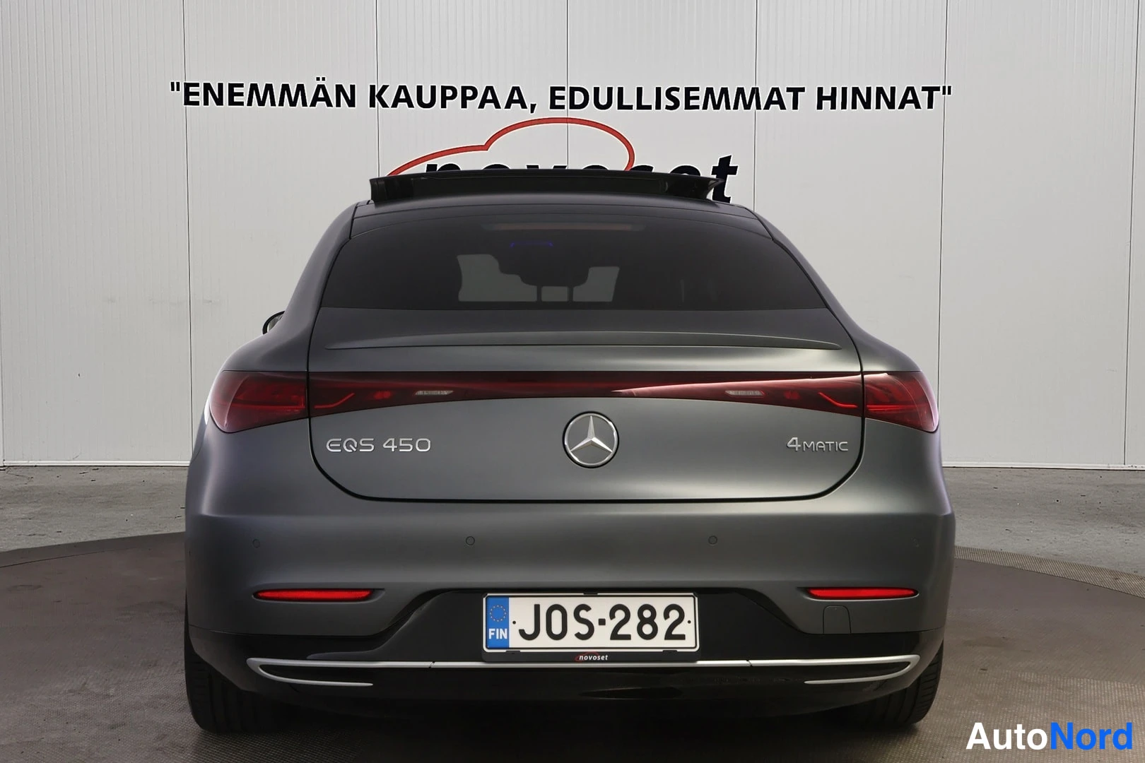 Takaa: Harmaan sedanin takapää suoraan takaa; takaluukussa merkinnät EQS 450 ja 4MATIC sekä tähti-merkki, rekisterikilpi, kattoluukku auki-asennossa näkyy katveessa.