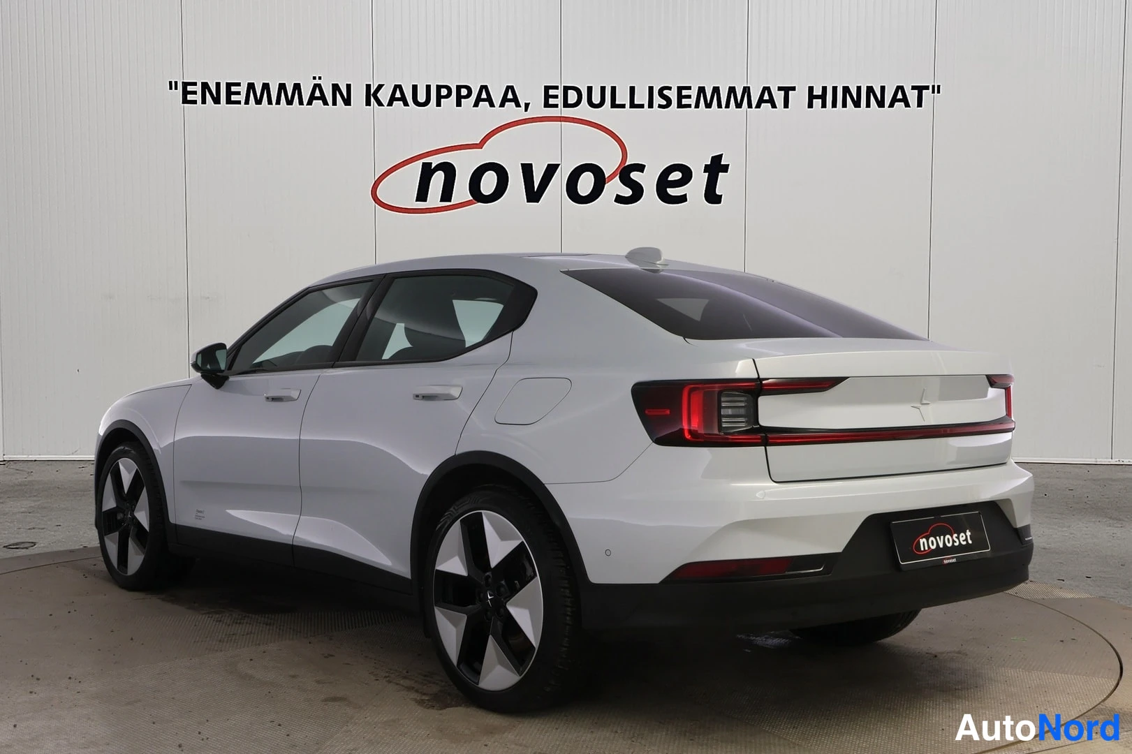 Takaviisto: Vaaleanharmaa Polestar 2 takakulmasta, perä oikealla: poikittainen punainen takavalo ja kevytmetallivanteet näkyvät.
