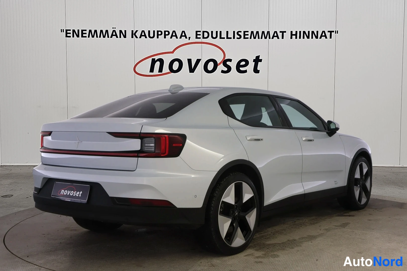 Takaviisto: Vaaleanharmaa Polestar 2 takakulmasta, perä vasemmalla: poikittainen punainen takavalo, ovet ja kevytmetallivanteet näkyvät.