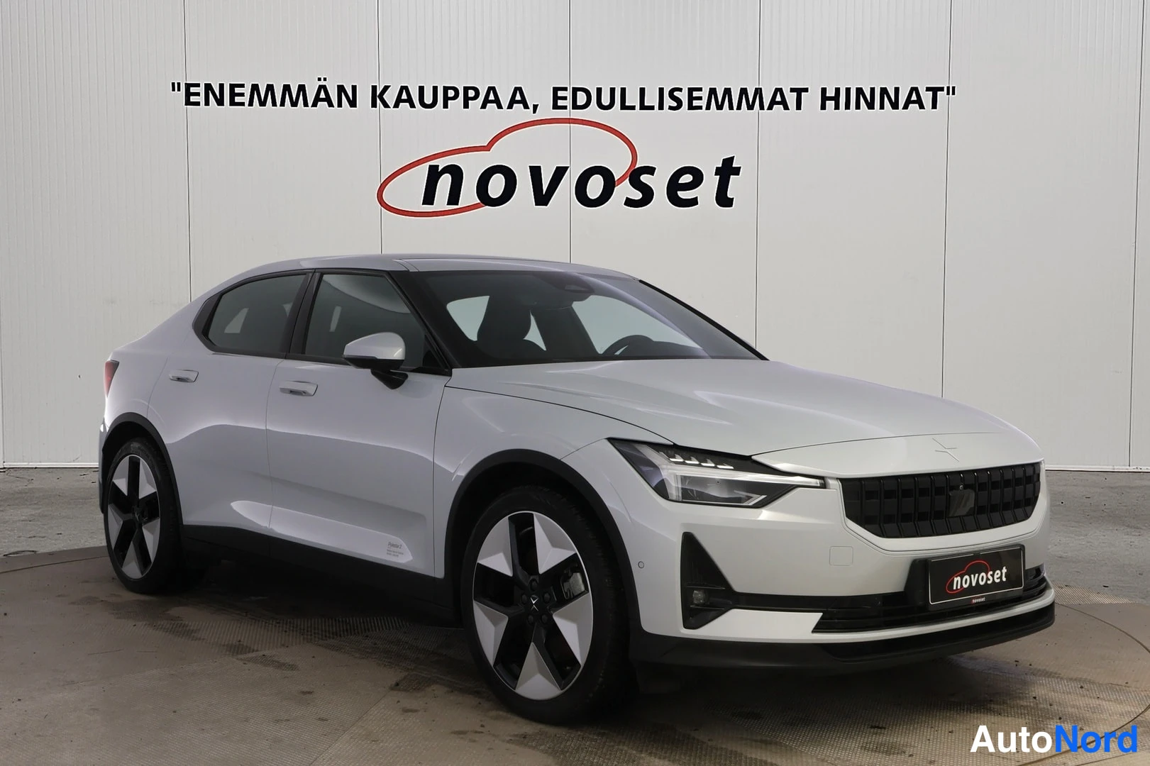 Etuviisto, nokka oikealle: Valkoinen Polestar 2 -henkilöauto kuvattuna etukolmannesnäkymänä, keula kuvan oikeassa reunassa. Etusäleikkö, ajovalot, konepelti ja auton vasen kylki ov