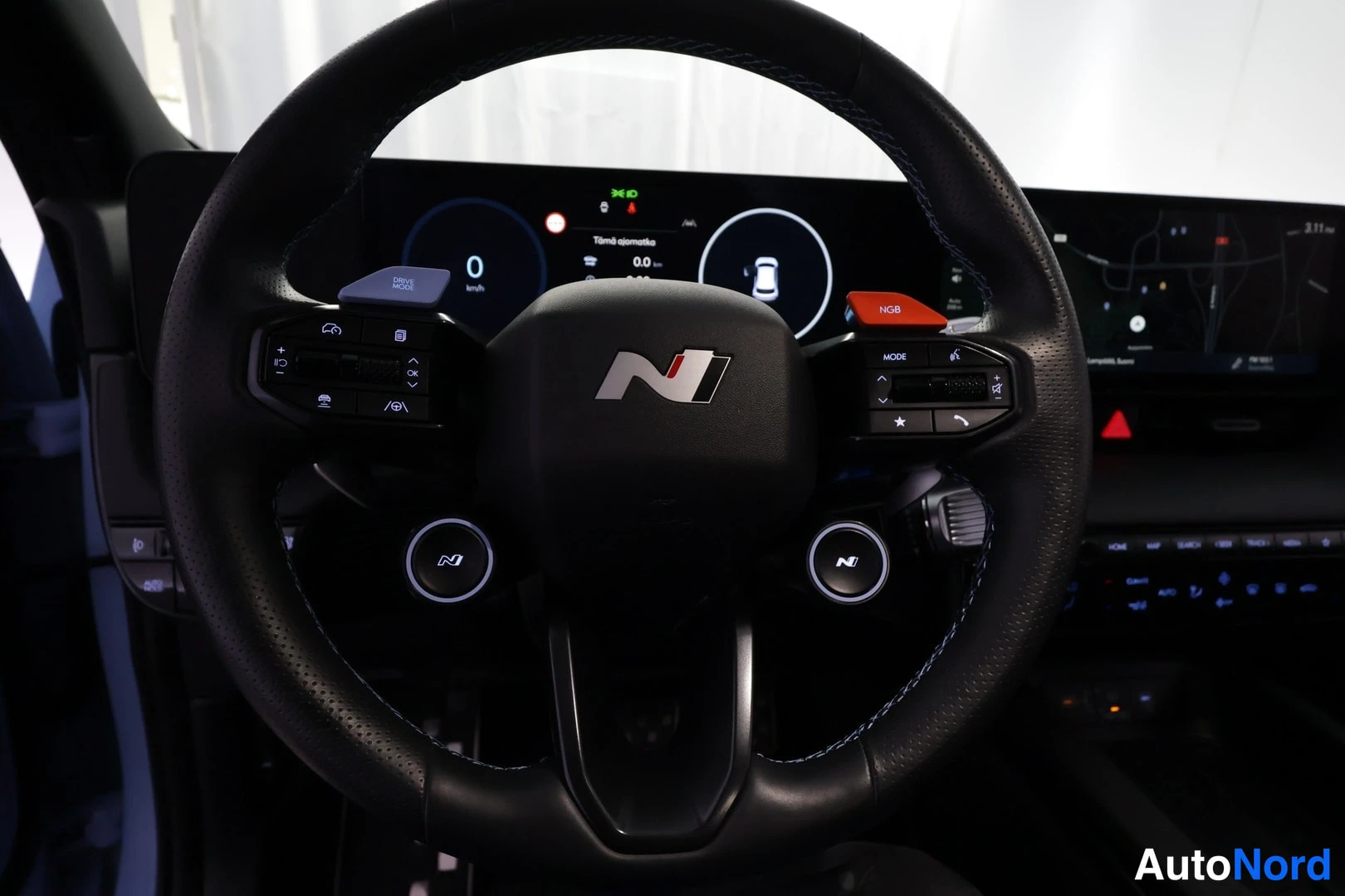 Etuistuimet: Full view of a sport steering wheel featuring dual paddle shifters, blue contrast stitching, central badge, and two illuminated circular N logos on the bottom s
