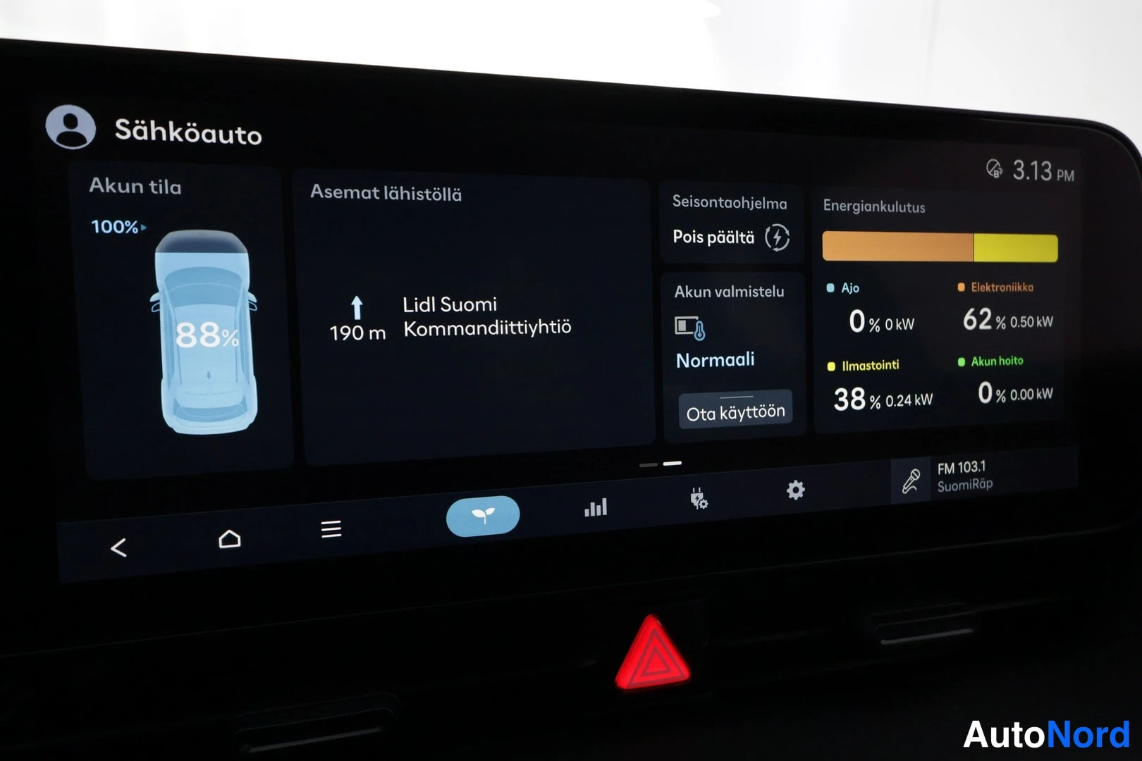 Muu: Infotainment-näyttö suomenkielisellä sähköauton tilanäkymällä: akun tila 100 % (88 % grafiikassa), lähin latausasema Lidl Suomi 190 m, energiankulutus ja FM 103