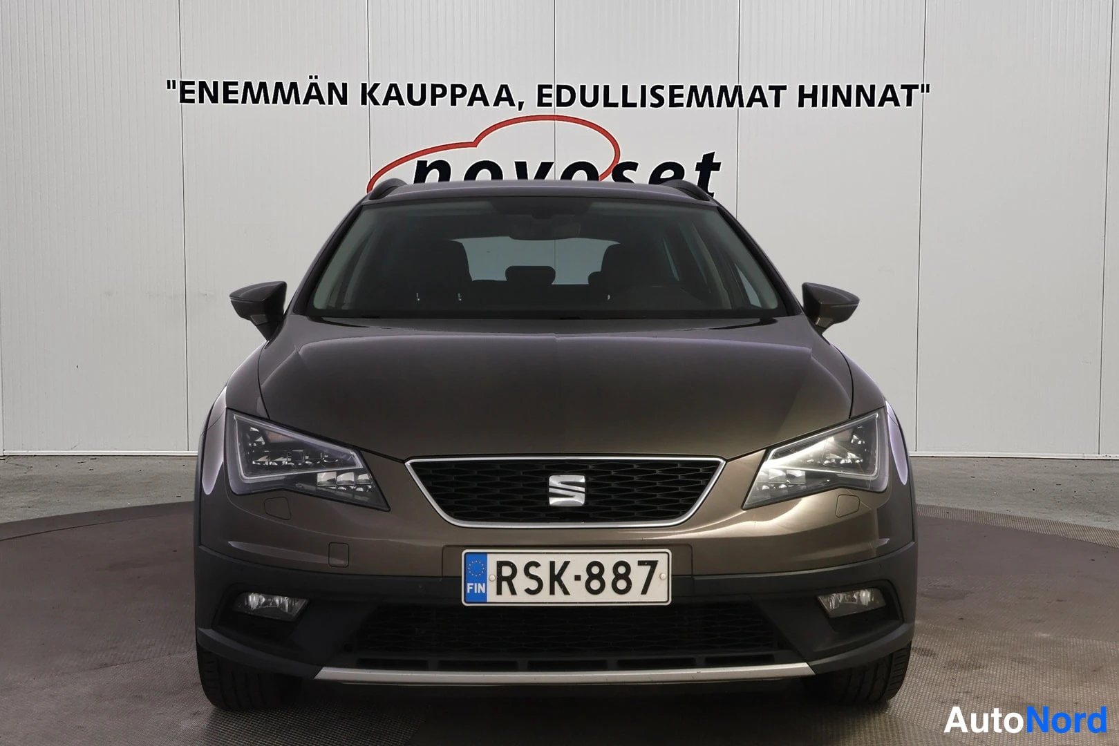 Edestä: Ruskean Seat Leon X-Perience -farmarin etupää suoraan edestä, Seat-merkki etusäleikössä, rekisterikilpi.
