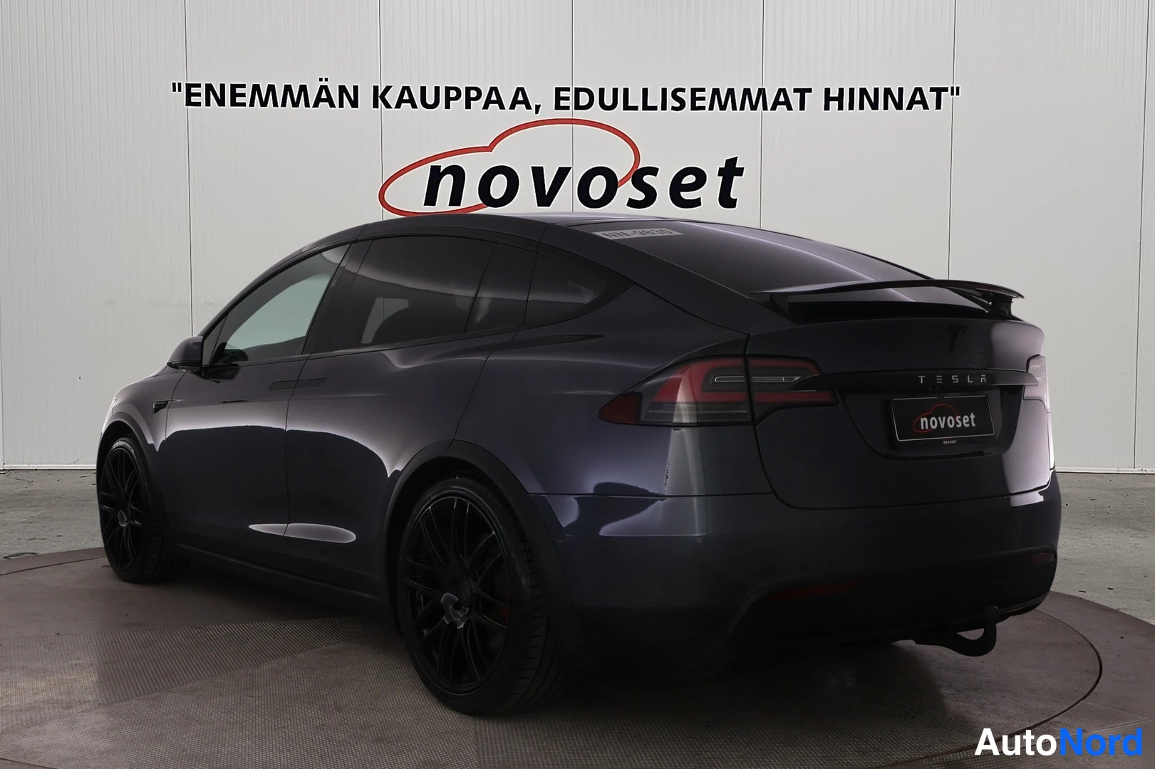 Takaviisto: Tesla Model X takaviisto oikealta, mustat vanteet ja novoset-kyltti