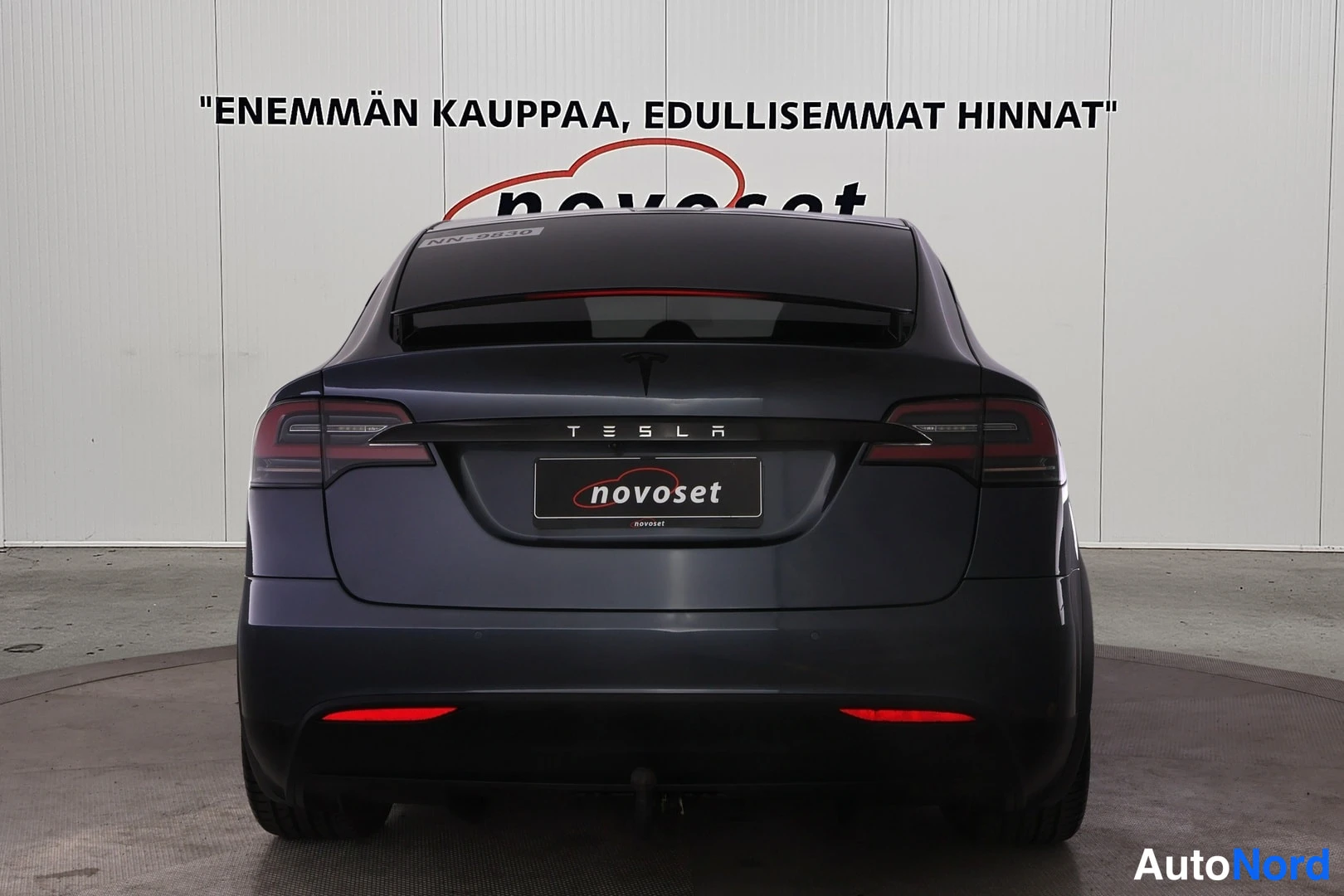 Takaa: Tesla Model X suoraan takaa, TESLA-teksti ja novoset-kyltti kannessa