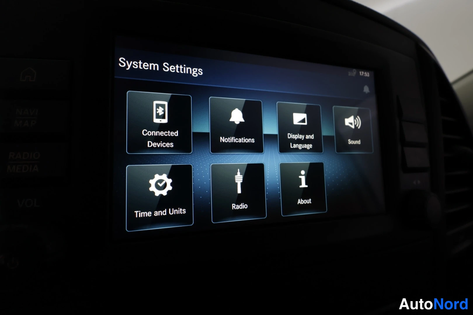 Yksityiskohta: Auton infotainment-näytön System Settings -valikko: Connected Devices, Notifications, Display and Language, Sound, Time and Units, Radio, About.