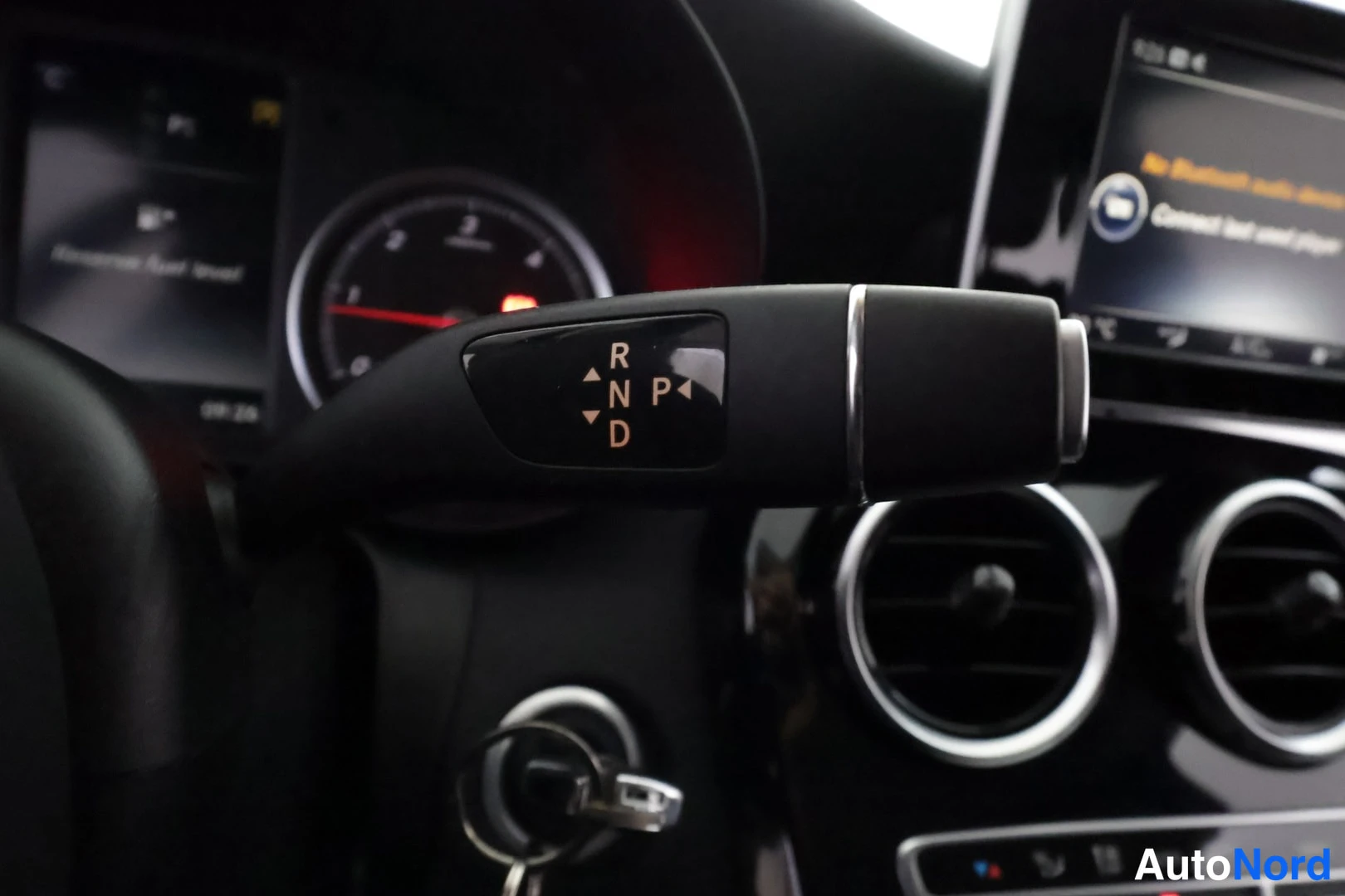 Muu: Sisätilakuva: automaattivaihteiston valitsinvipu ohjaustangossa merkeillä R, N, D ja P. Taustalla kierrosmittari, näyttö jossa lukee 'Bluetooth audio' ja 'Conne