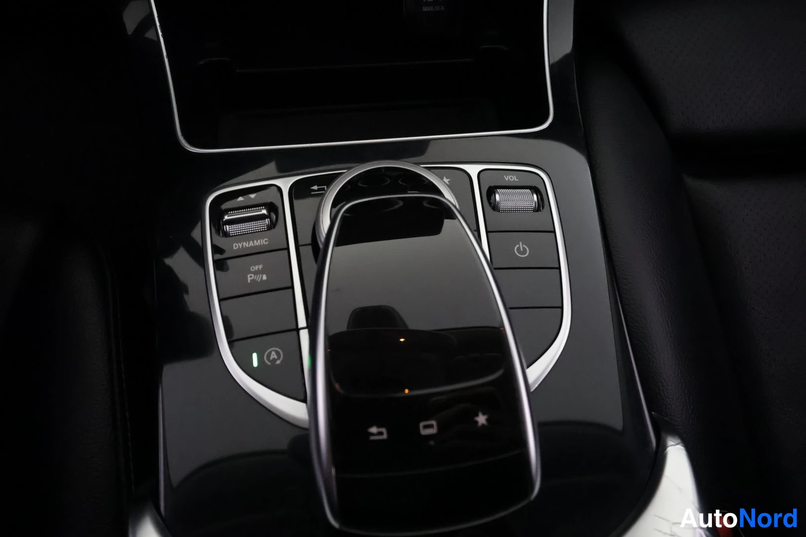 Muu: Sisäkuva Mercedes-Benzin keskikonsolista:(touchpad-ohjain), DYNAMIC-valitsin, VOL-säädin ja virran Katzakin symboli.